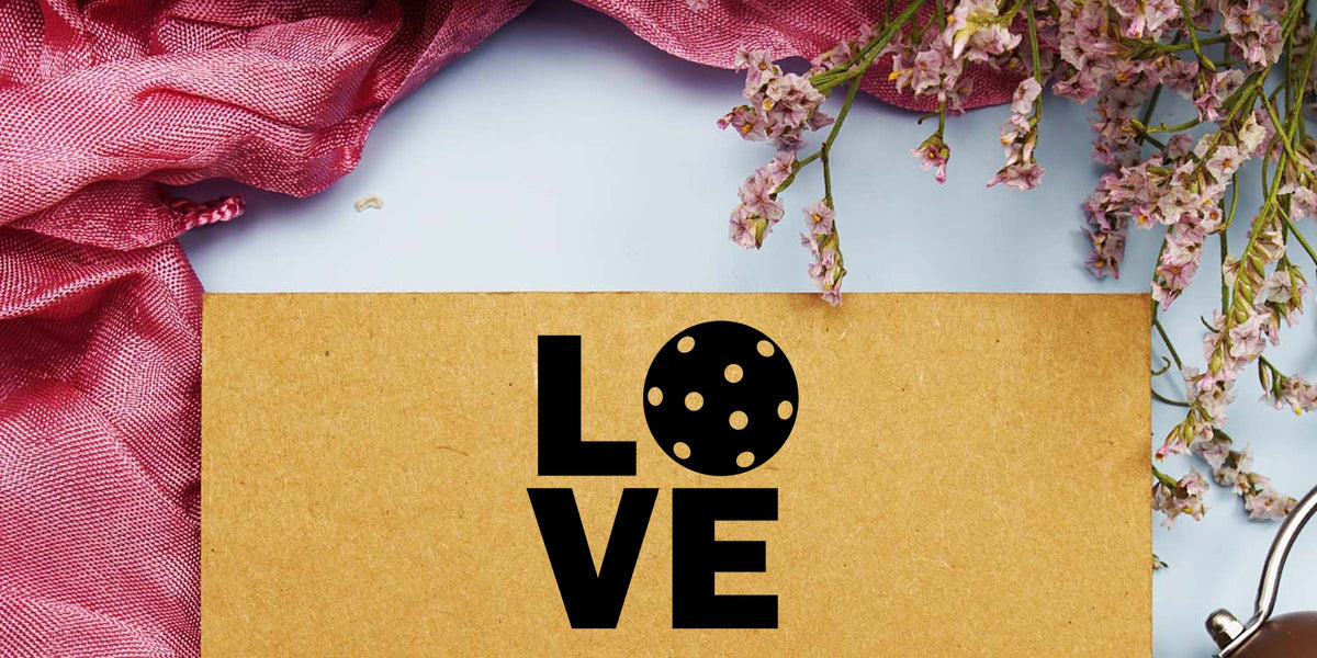 Kraft paper with bold LOVE lettering, pink fabric, and delicate dried flowers on a light background