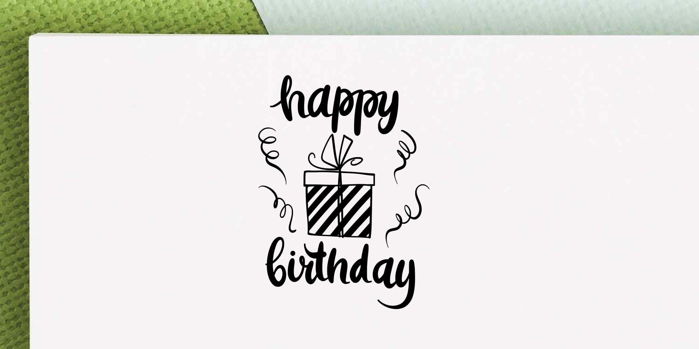 Happy birthday greeting card design with black script text, a striped gift box, and confetti on a white background with green textured backdrop