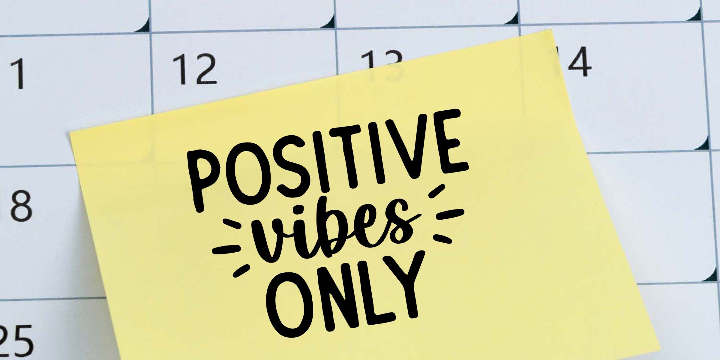 Yellow sticky note on a calendar with bold black text reading “Positive Vibes Only”