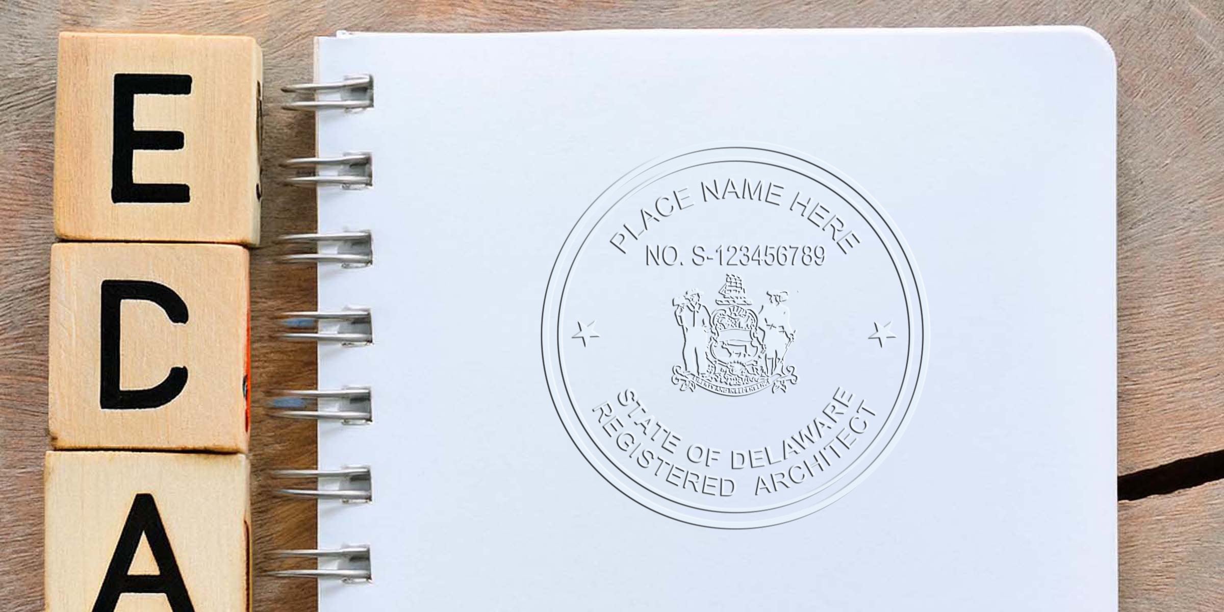 Delaware architect seal on notebook with wooden blocks spelling ECA, showcasing Delaware registered architect seal and its size specifications.