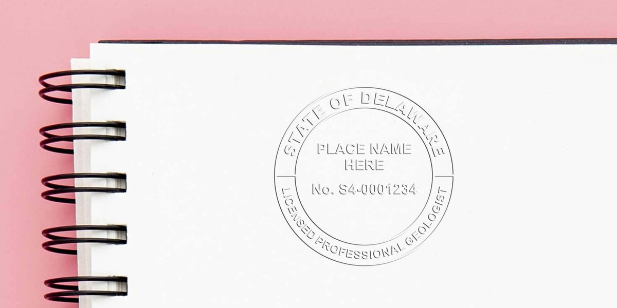 Delaware licensed professional geologist embossed seal on white spiral notebook with pink background, showcasing Delaware geologist stamp cost and pricing.
