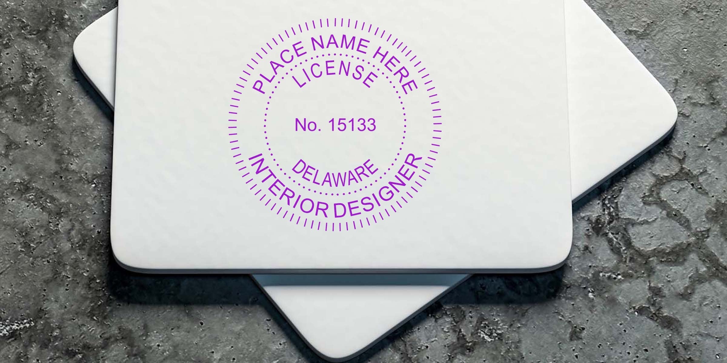 Delaware interior designer license stamps on white cards rest on textured concrete, showcasing Delaware’s interior designer licensing process.