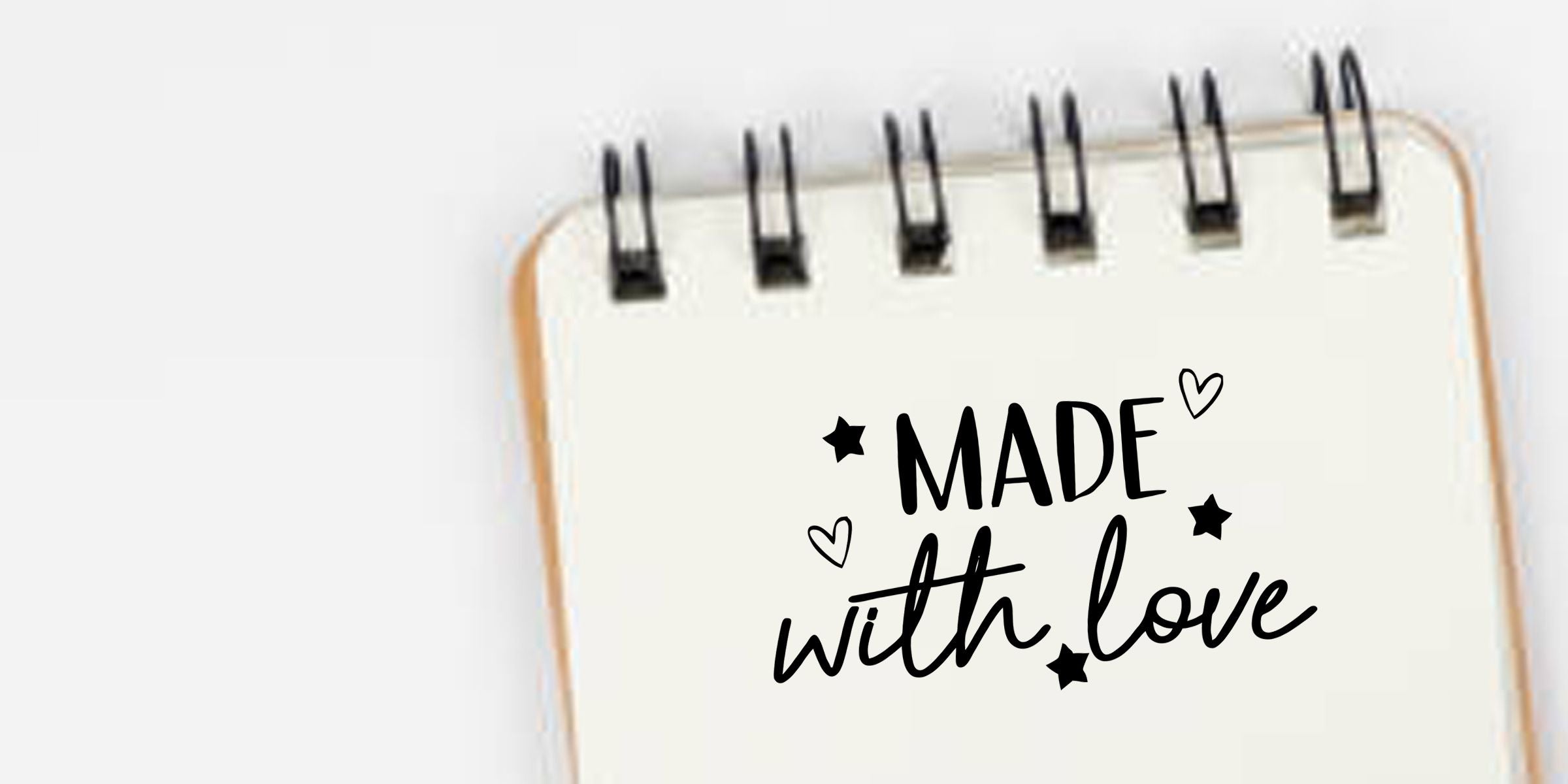 Spiral notebook with “Made with love” hand-lettered design, hearts, and stars on a clean white background