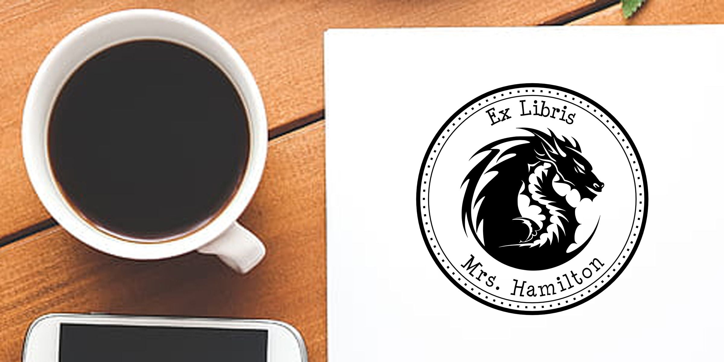 Coffee cup beside personalized Ex Libris lion bookplate with Mrs. Hamilton on a wooden desk
