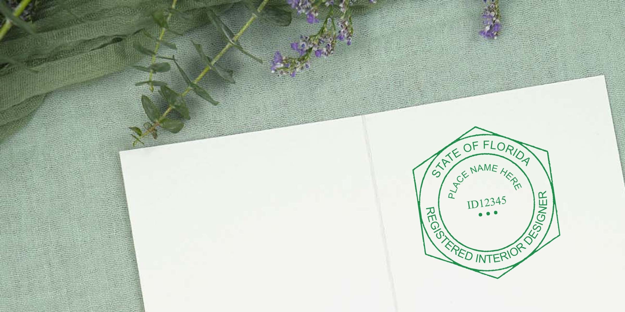 Registered interior designer certification stamp on white paper with Florida interior design seal, placed on green fabric and floral background.