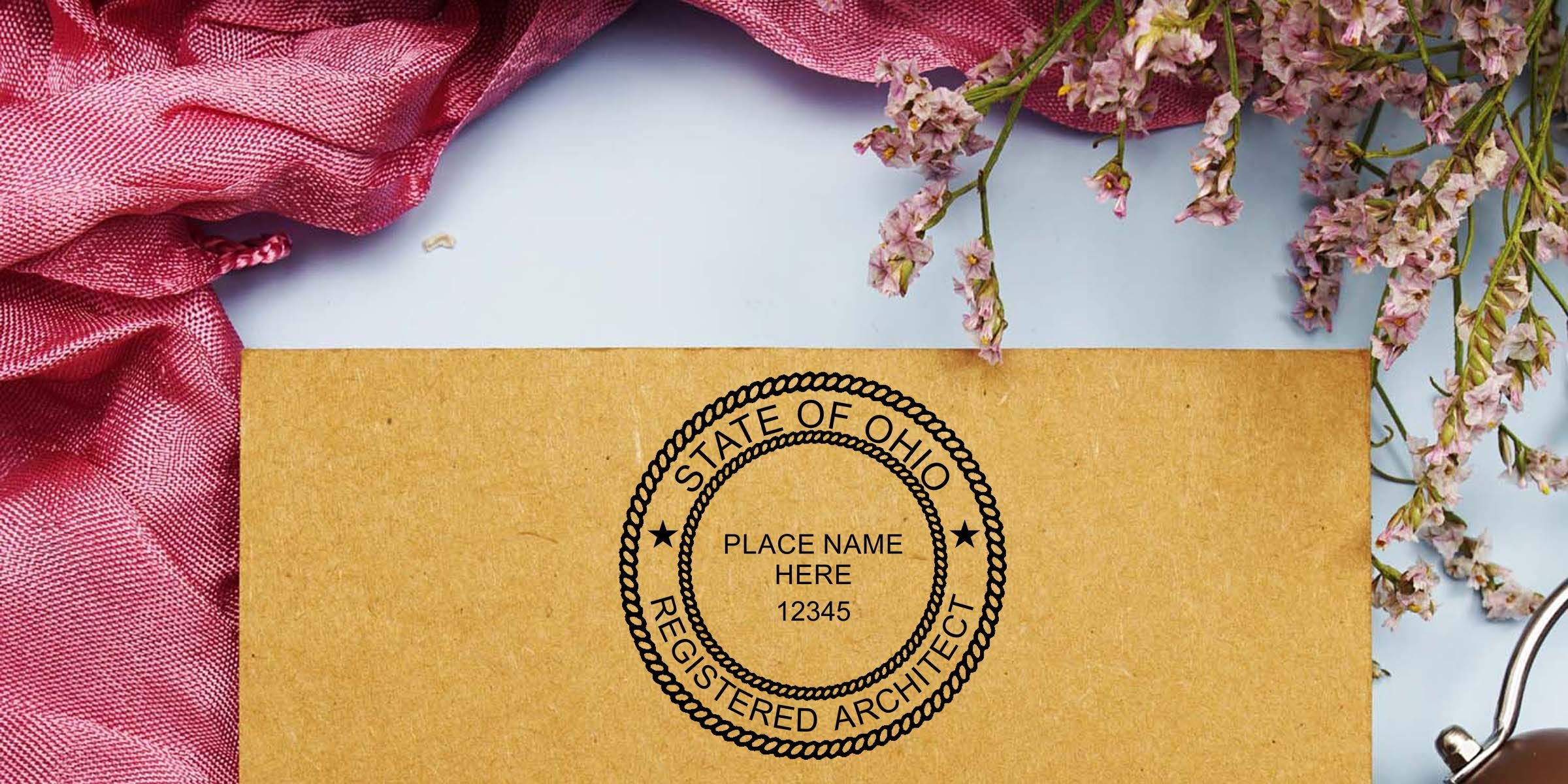 Kraft envelope with State of Ohio Registered Architect stamp, pink fabric, and delicate dried flowers on a light background