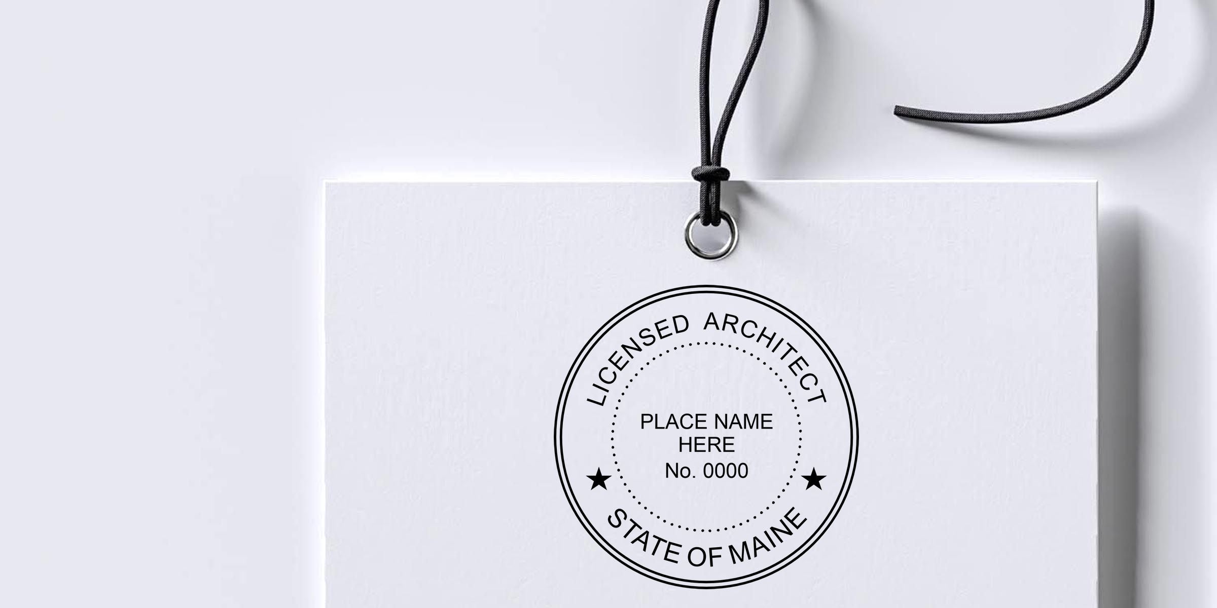 White hanging paper tag with a black circular “Licensed Architect State of Maine” seal and customizable place name and license number placeholder.