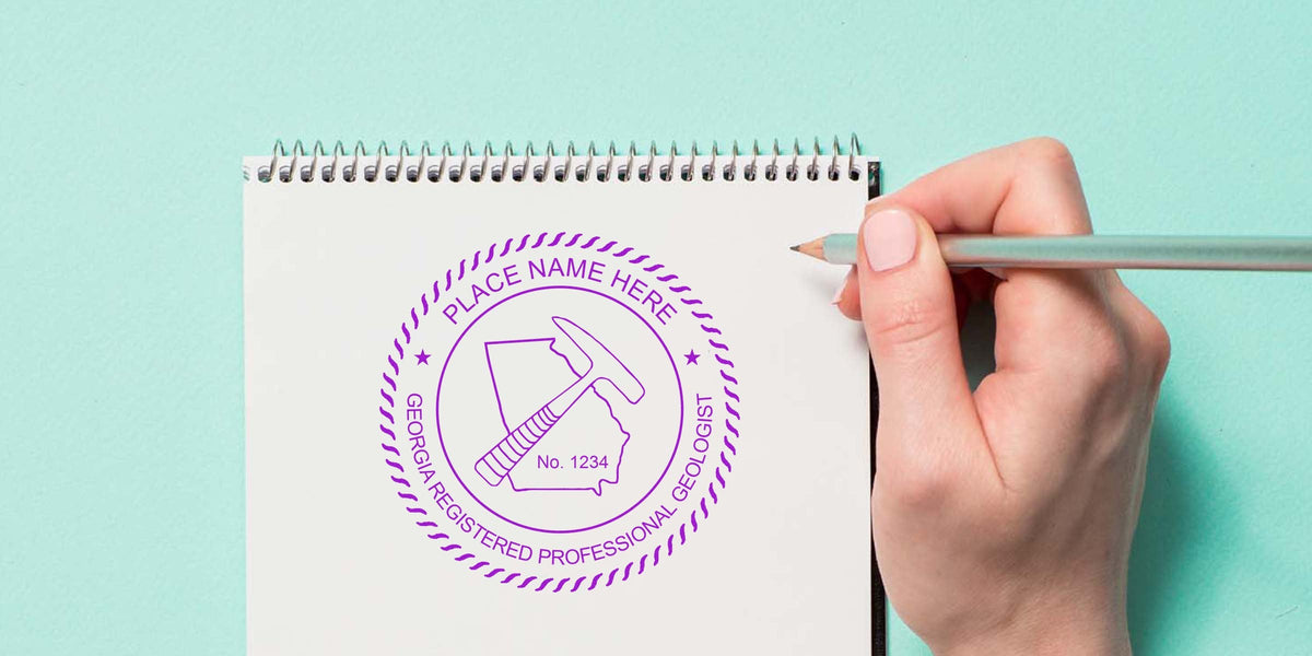 Hand holding pencil on notebook with Georgia geologist seal stamp, highlighting seal design tips.