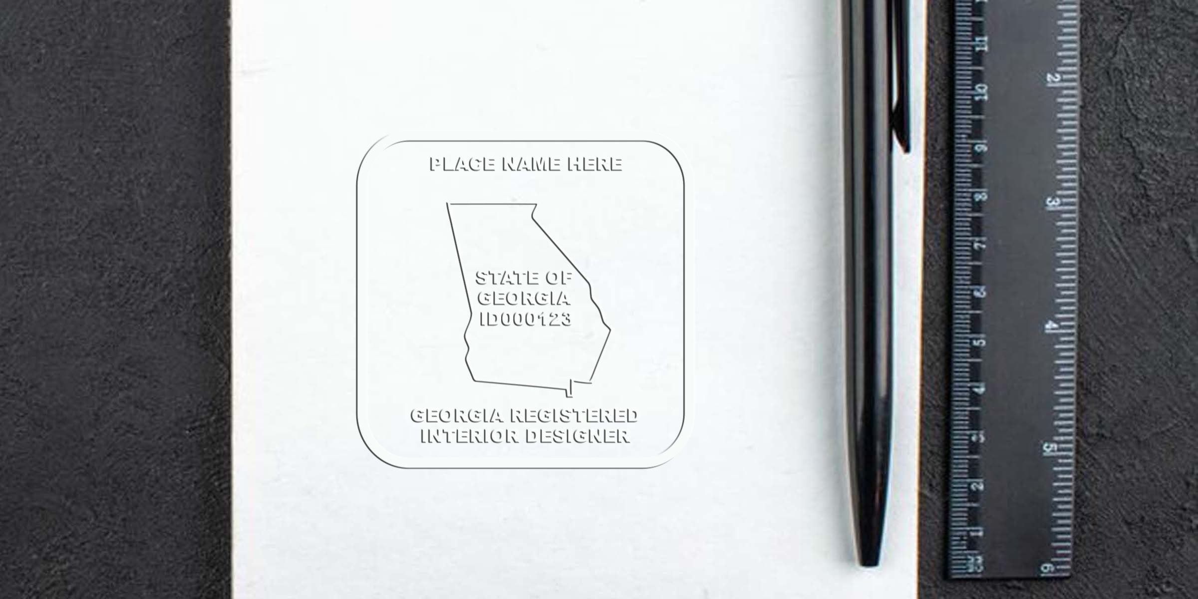 Georgia seal embossers pressing an official document with a registered interior designer certification stamp on white paper, alongside a black pen and ruler.