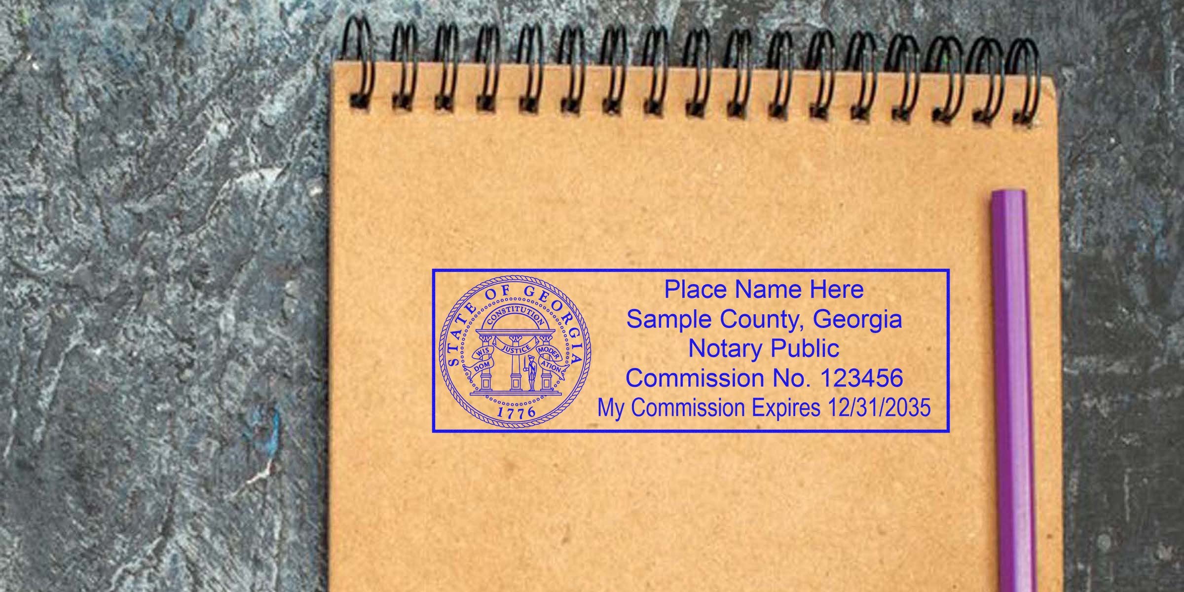 Georgia notary stamp on a brown spiral notebook with a purple pen, showing a notary seal on a textured gray surface.