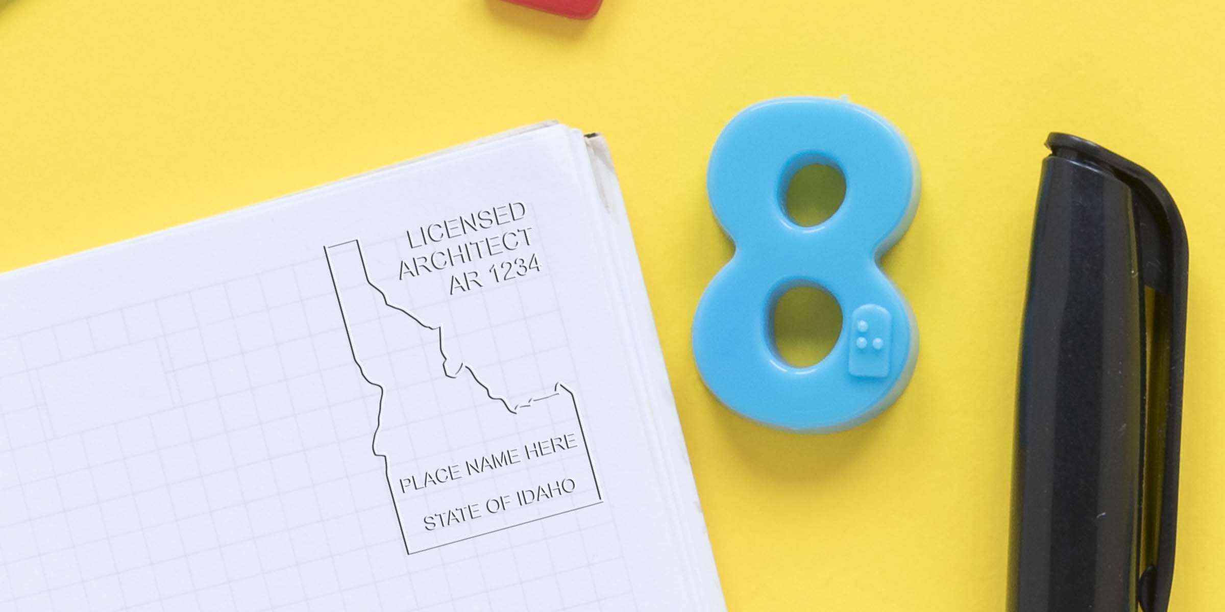 Idaho architect stamp options with a custom stamp on blueprint paper, showing a blue number eight and black stapler on a yellow background.