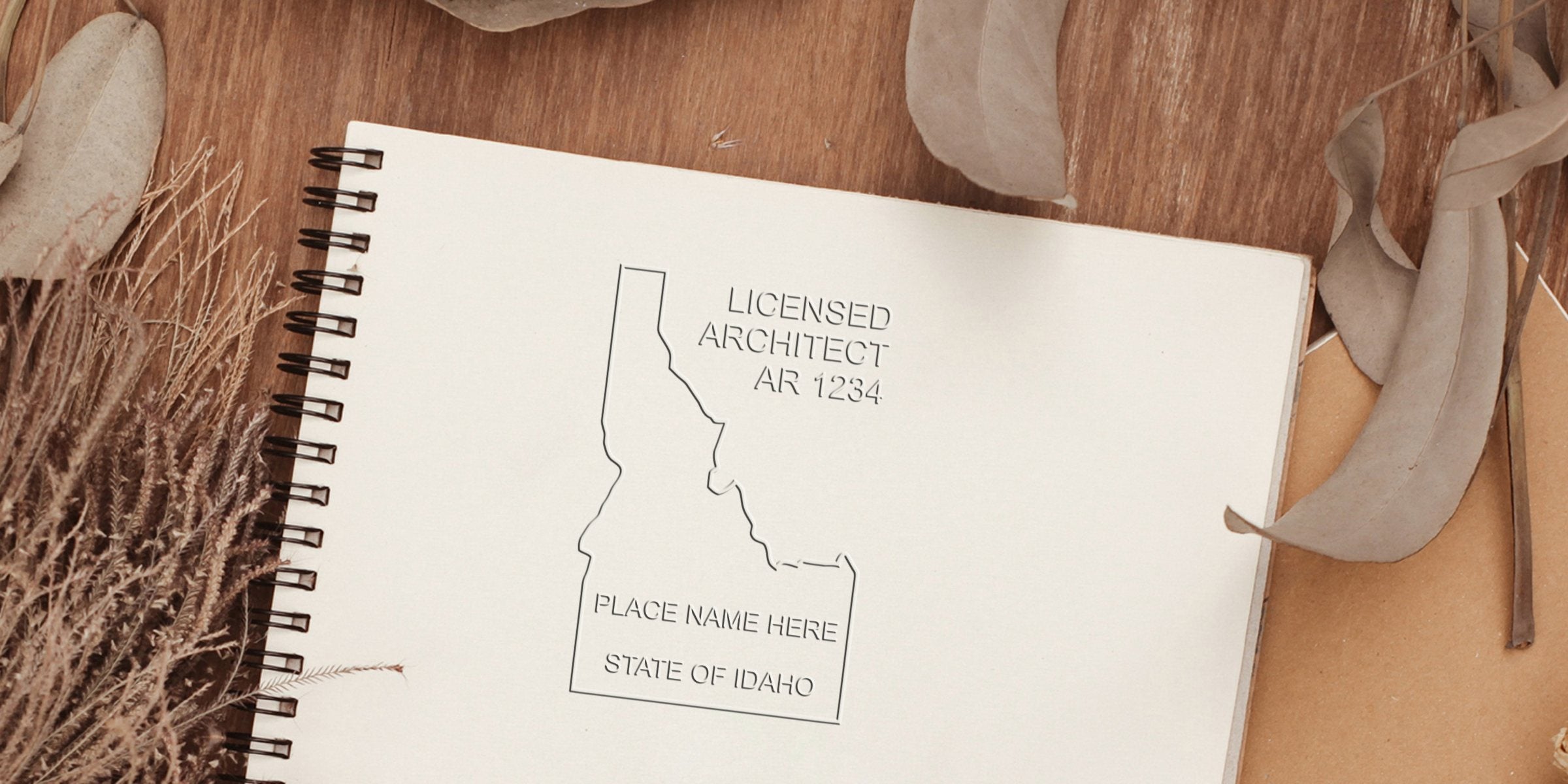 Idaho licensed architect stamp on spiral notebook with dried leaves and rustic wood background, highlighting Idaho architect seal rules and tips.