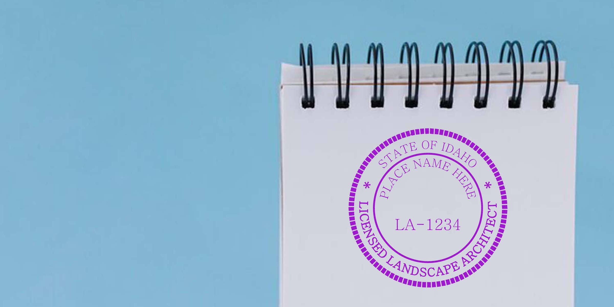 Idaho landscape architect stamp on white spiral notebook featuring seal design essentials on blue background.