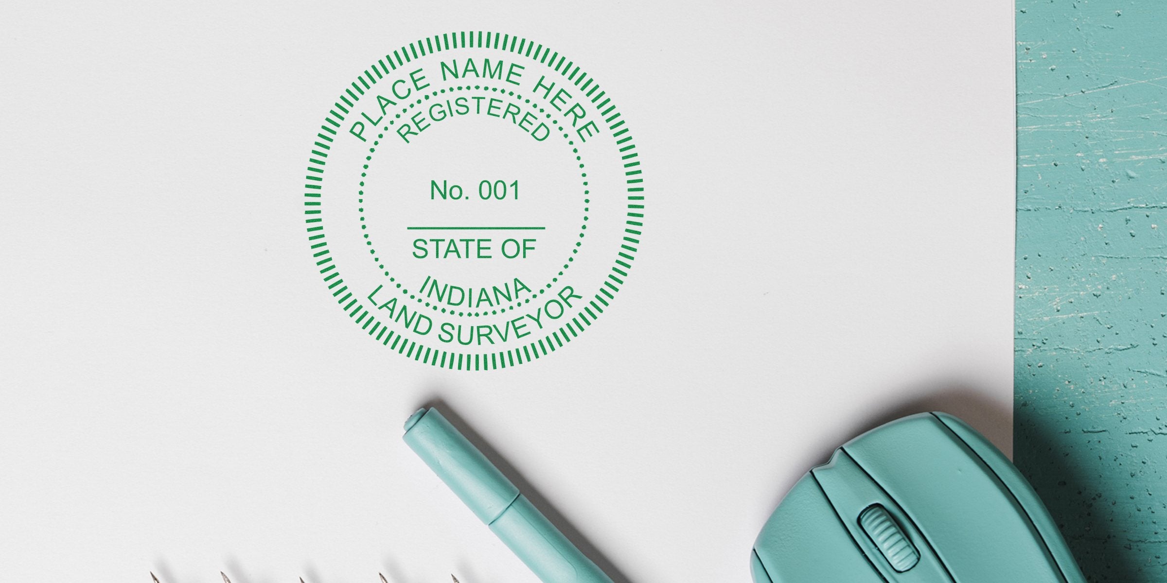 Indiana land surveyor stamp on white paper, ideal size, with teal pen and computer mouse on turquoise wooden desk.