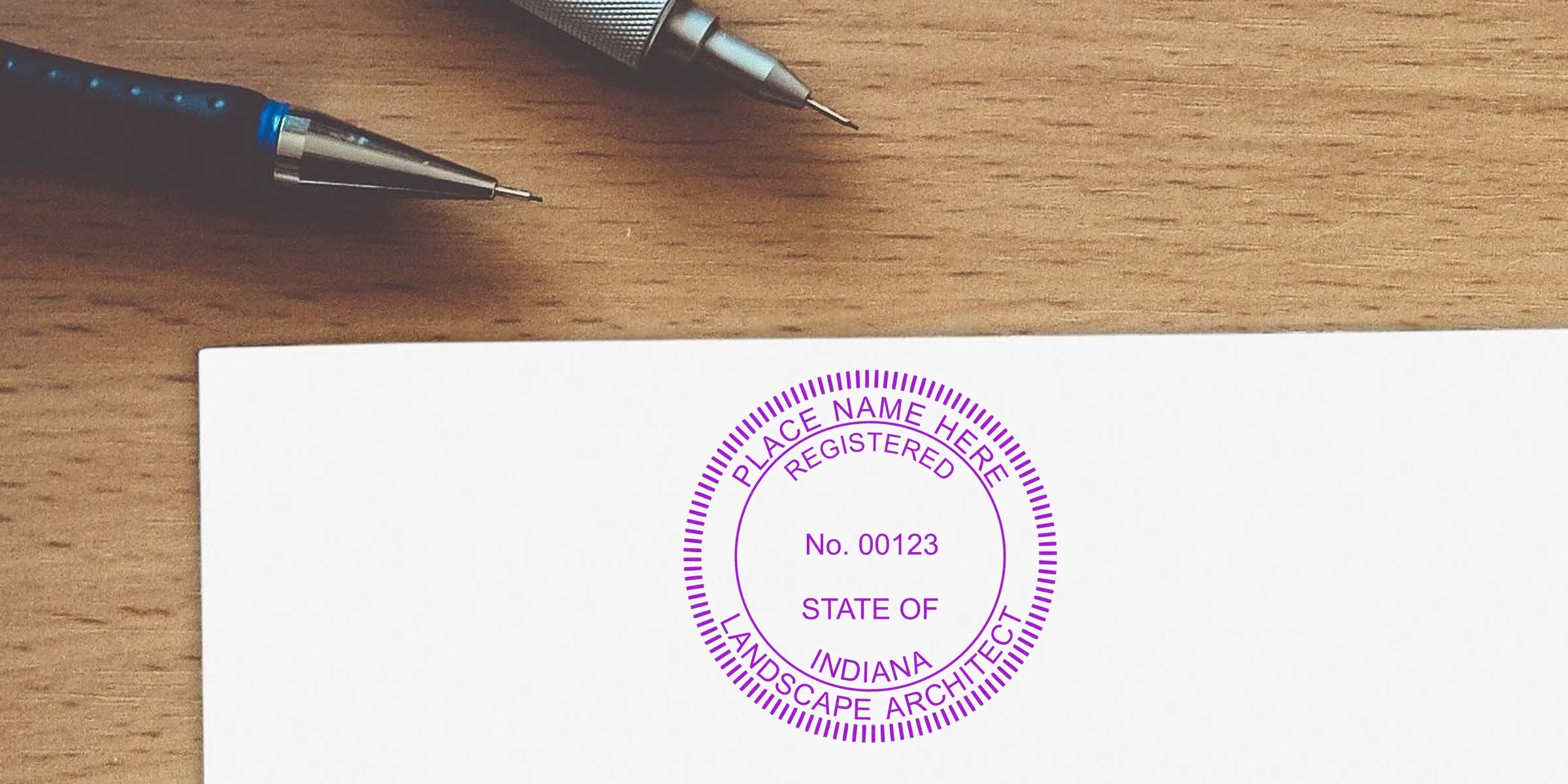 Indiana landscape architect license stamp on paper with pens on wooden desk, showing tips for applying the landscape architect stamp.