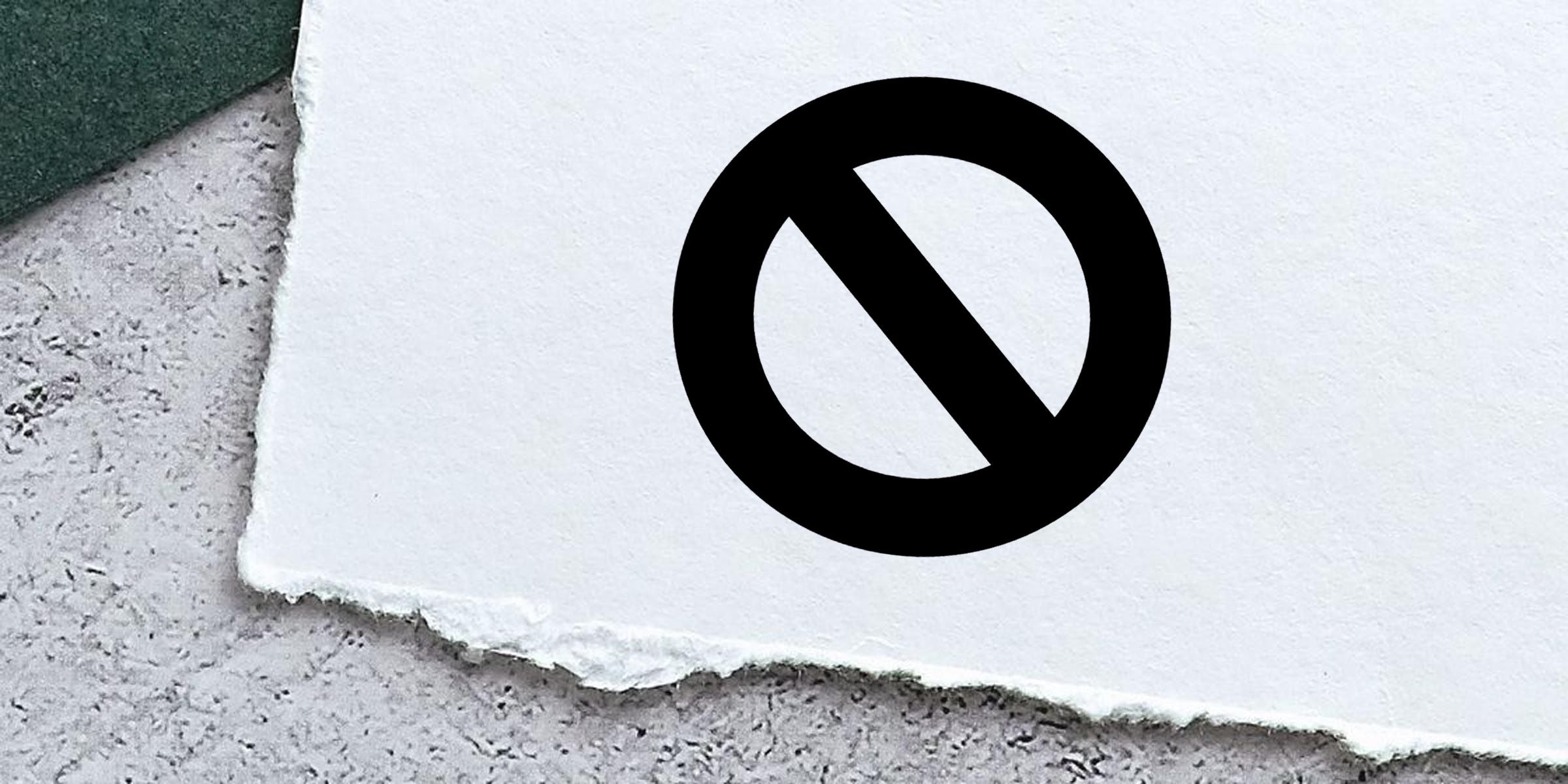 Black prohibition symbol on torn white paper against a textured gray background, representing no entry or restriction sign