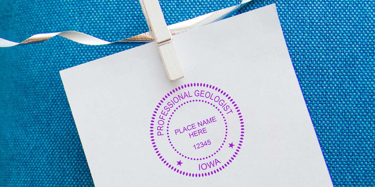Iowa geologist stamp embossed on white paper, held by clothespin against blue textured background, showcasing professional geologist embosser guide.