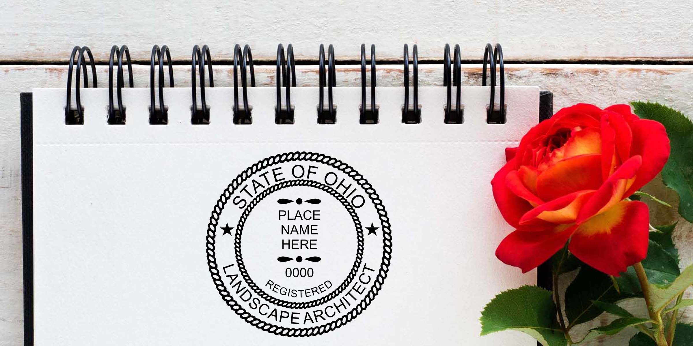 Spiral notebook with customizable State of Ohio landscape architect seal beside a red rose on a rustic white wooden background