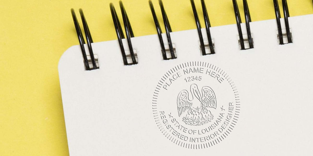 Louisiana interior designer seal embossed on a white spiral notebook against a yellow background, symbolizing Louisiana interior design certification.