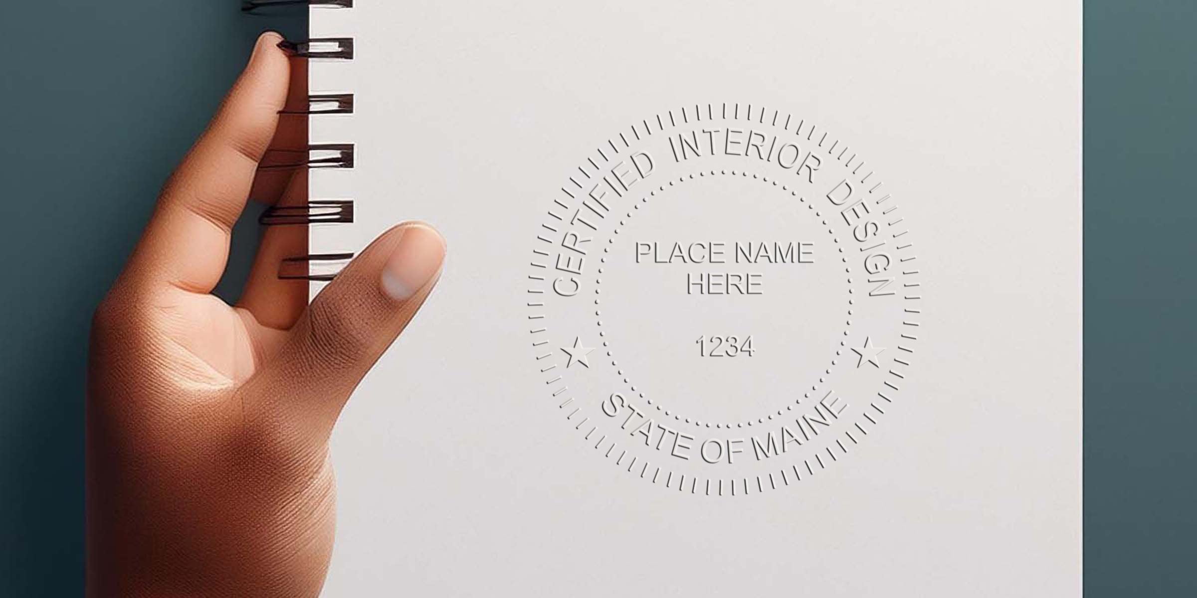 Hand holding a spiral notebook stamped with a Maine interior designer seal, showing certified interior design licensing in Maine.