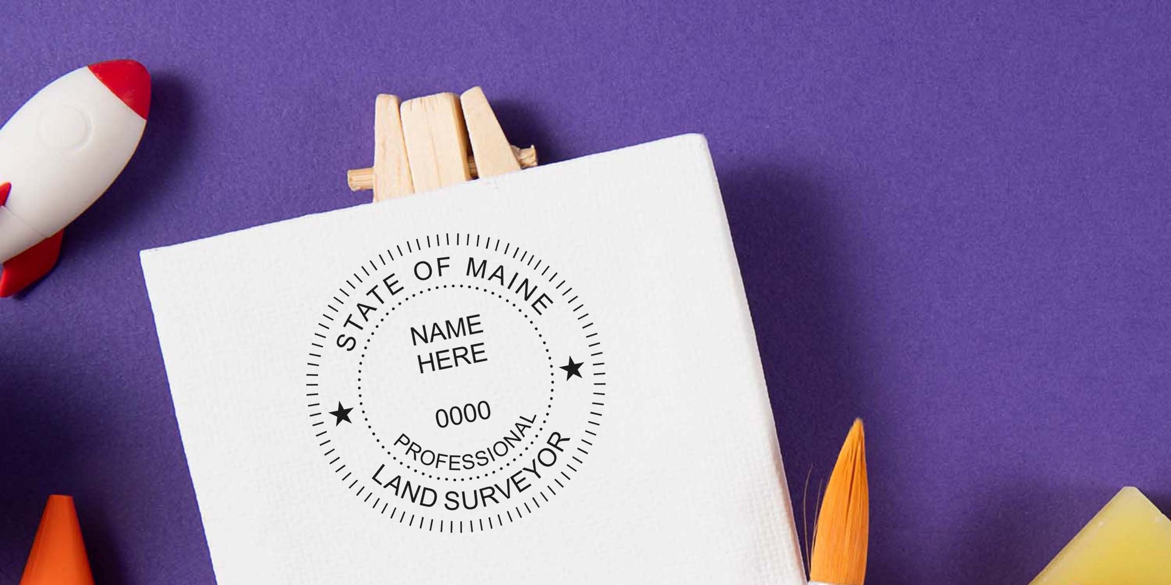 Maine land surveyor seal on white paper with purple background and rocket toy, displaying seal specs and professional certification stamp.