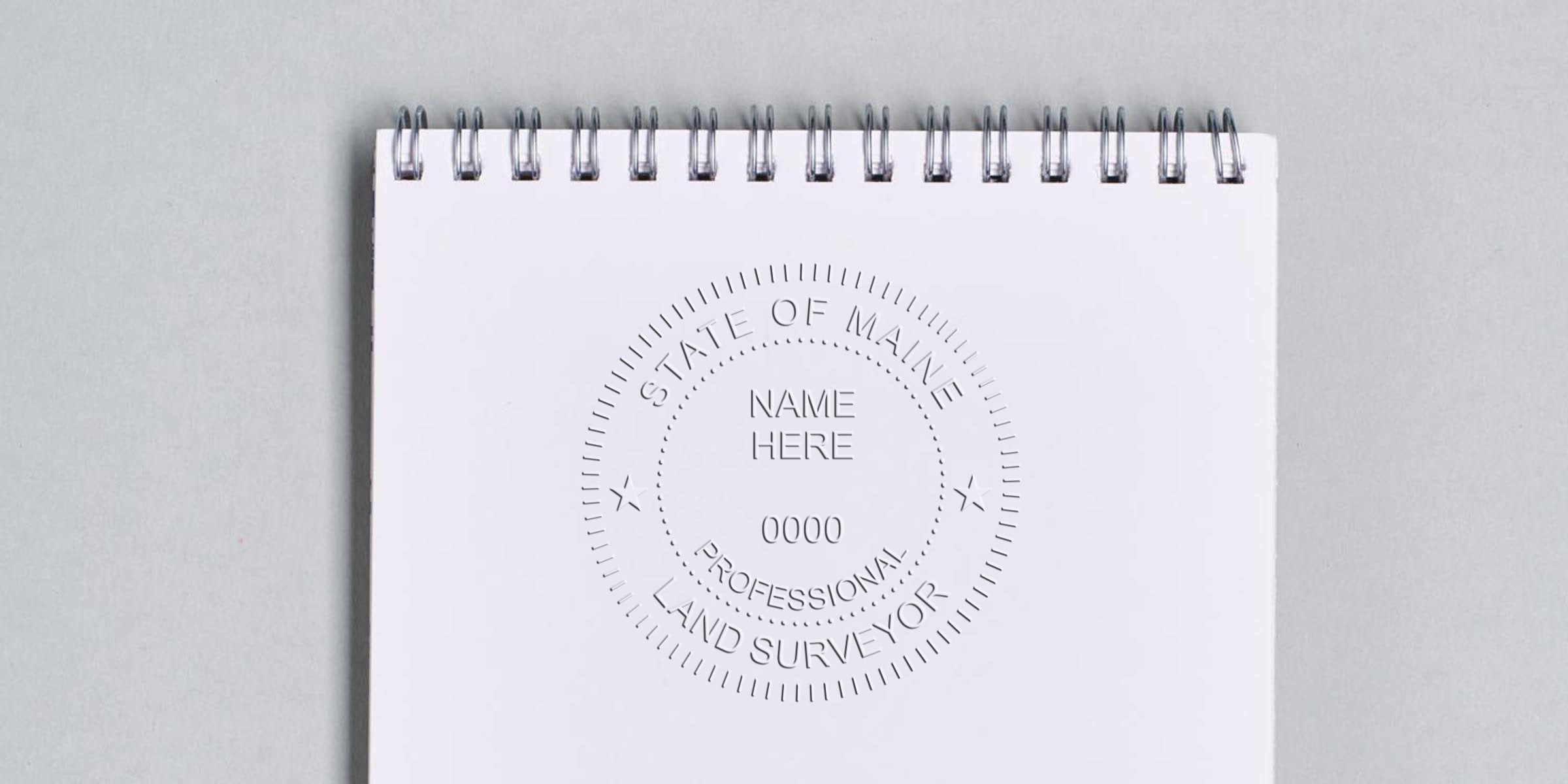 State of Maine professional land surveyor embossed seal on white spiral notebook, highlighting the seal and benefits of using a surveyor embosser for land surveying certification.