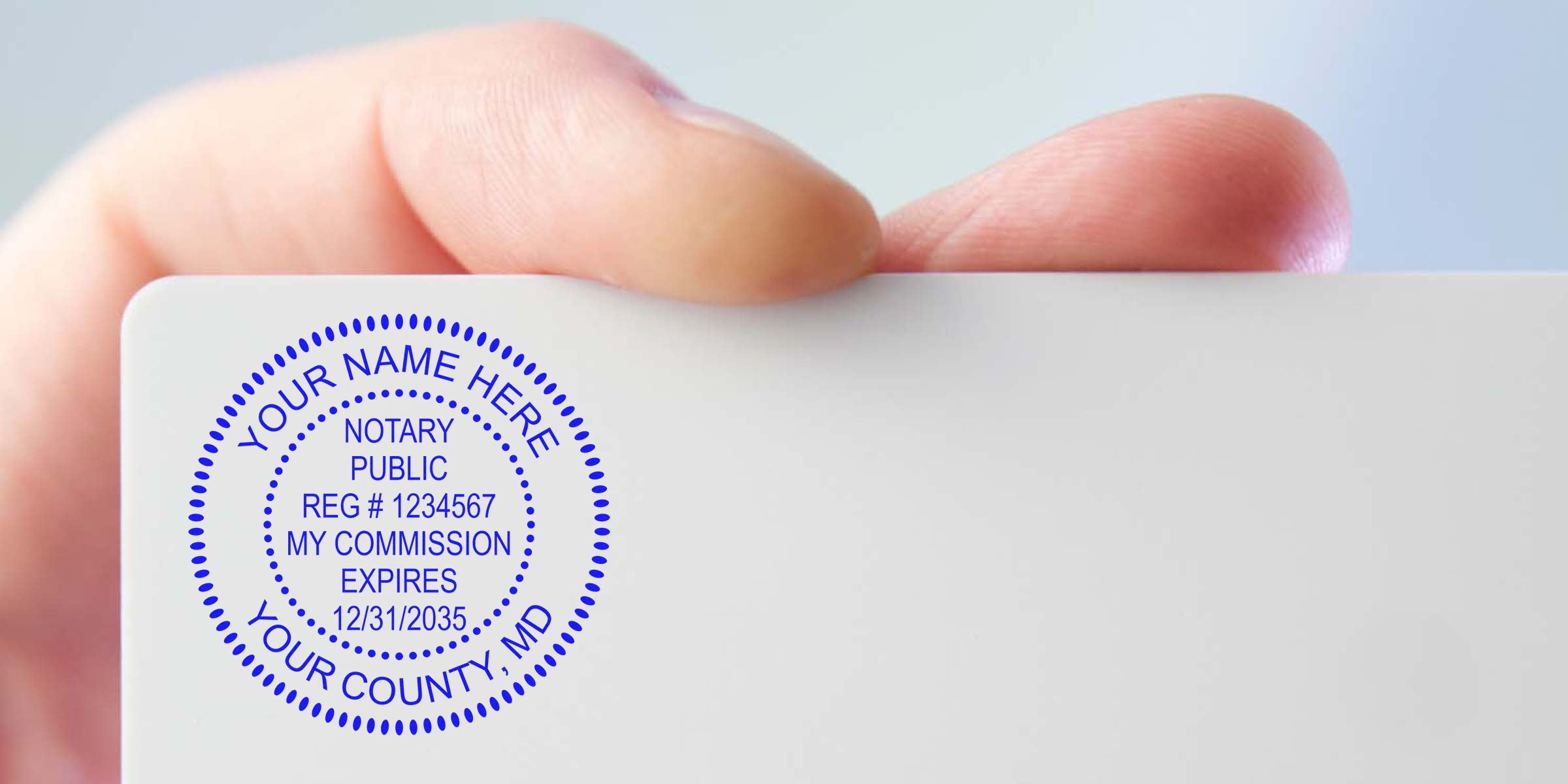 Maryland notary seal and quality stamp shown on a notary public commission card with registration number and expiration date, held between fingers.