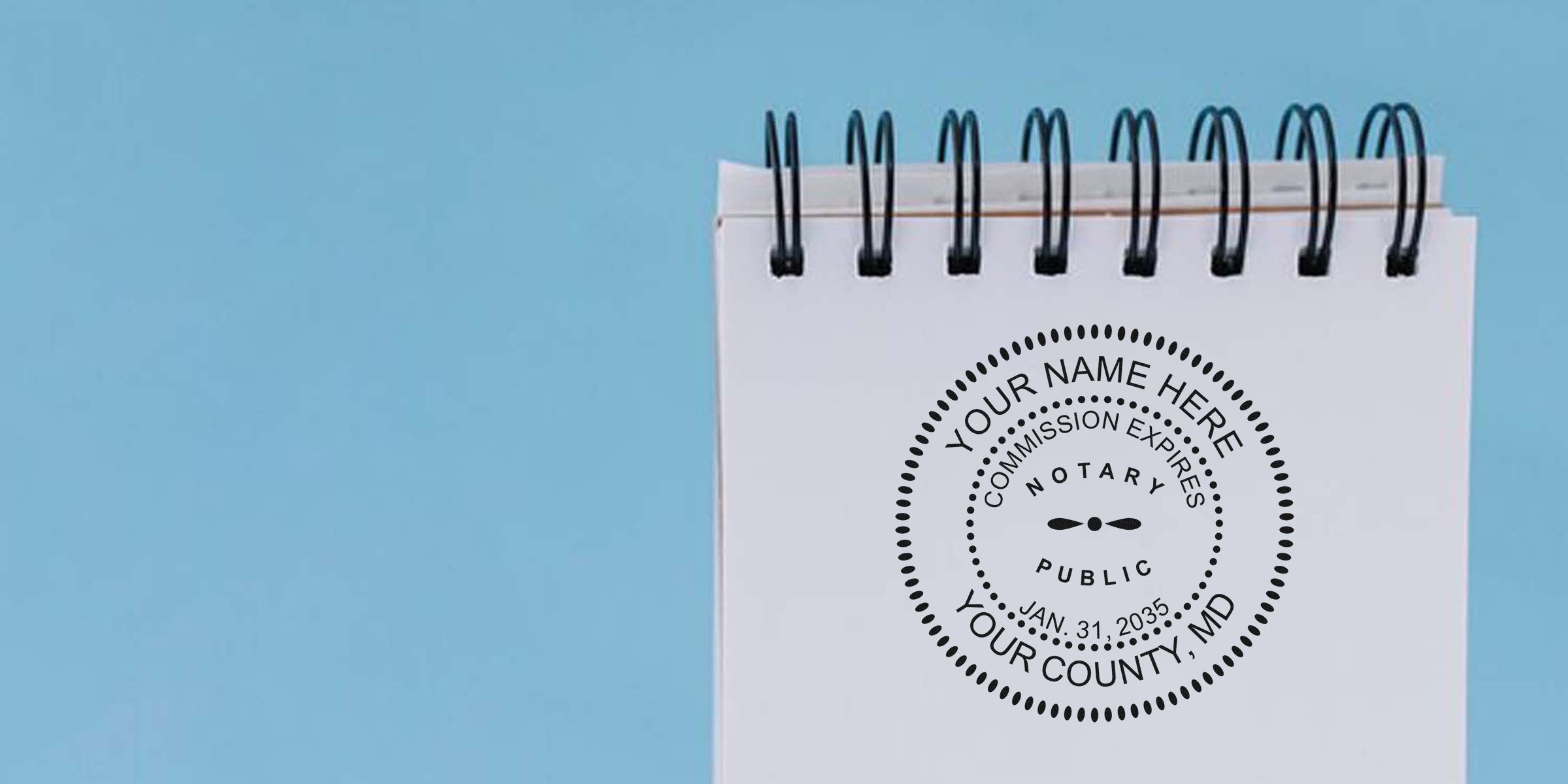 Custom Maryland notary stamp on white spiral notebook with blue background, personalized notary seal, essential Maryland notary supplies, and public tools.