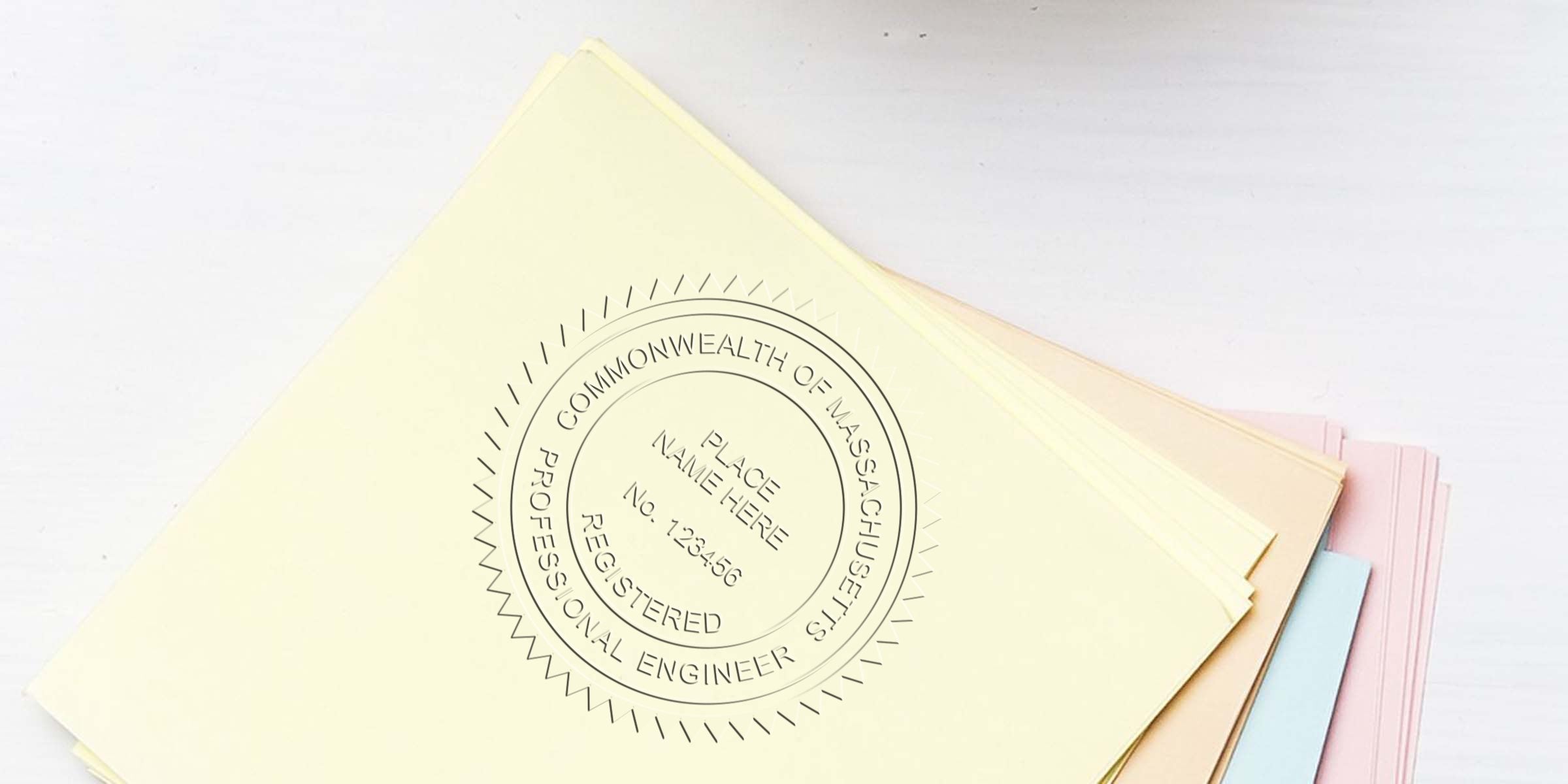 Stack of professional engineer certificates with Massachusetts engineer stamp and embosser, topped by a document bearing the Commonwealth of Massachusetts seal.