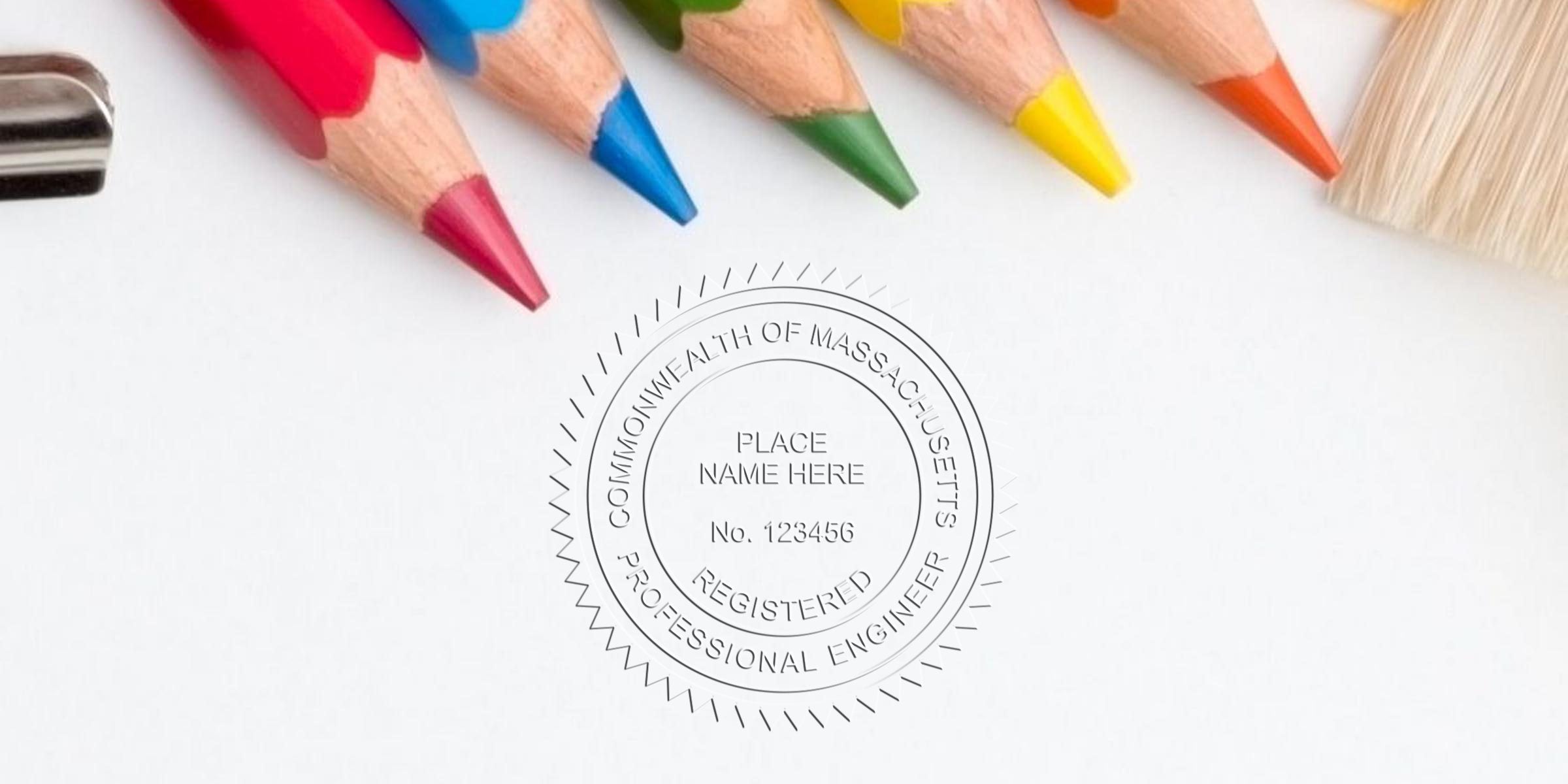 Colored pencils and paintbrush on white paper with embossed Massachusetts professional engineer seal, highlighting custom engineer seals and Massachusetts engineer stamps.