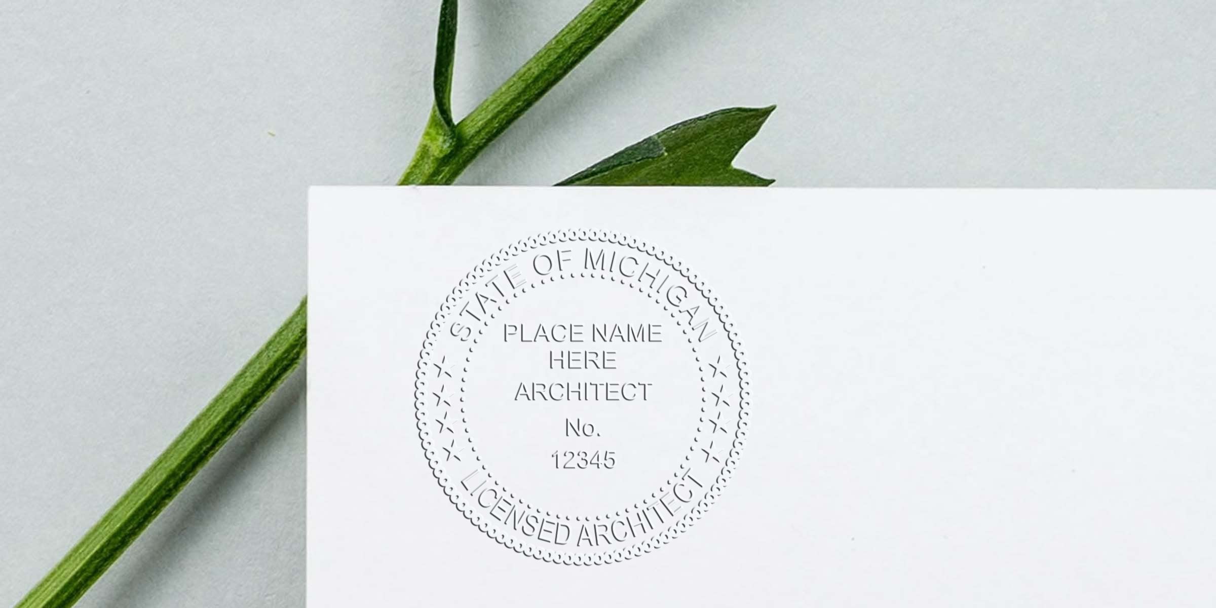 Michigan architect seal embossed on white paper with a green leaf background, made using an architect seal embosser.