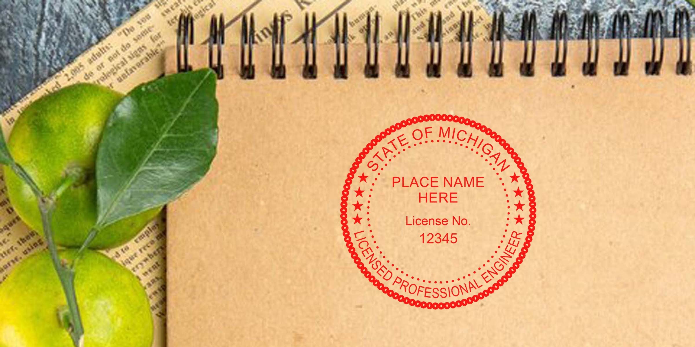 Michigan engineering seal stamped on a brown spiral notebook with green citrus fruits and leaves, set on a newspaper, emphasizing engineering seal requirements.