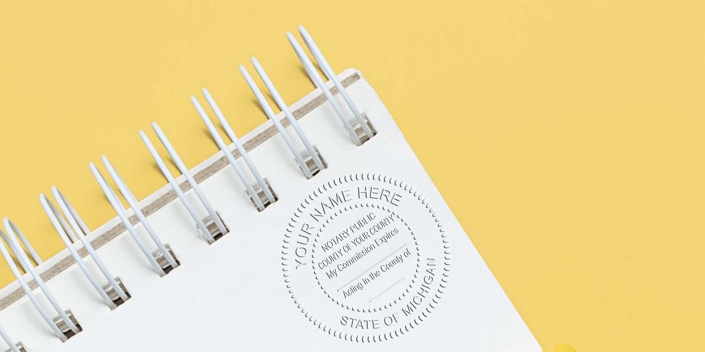 Spiral-bound notary journal with embossed seal on yellow background, featuring Michigan notary stamps and essential supplies.