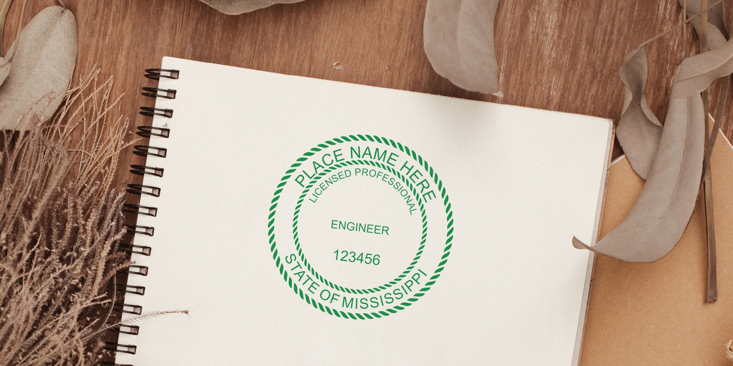 Licensed professional engineer stamp with Mississippi engineering seal on notebook, dried leaves, and wooden background, adhering to engineering seal design guidelines.
