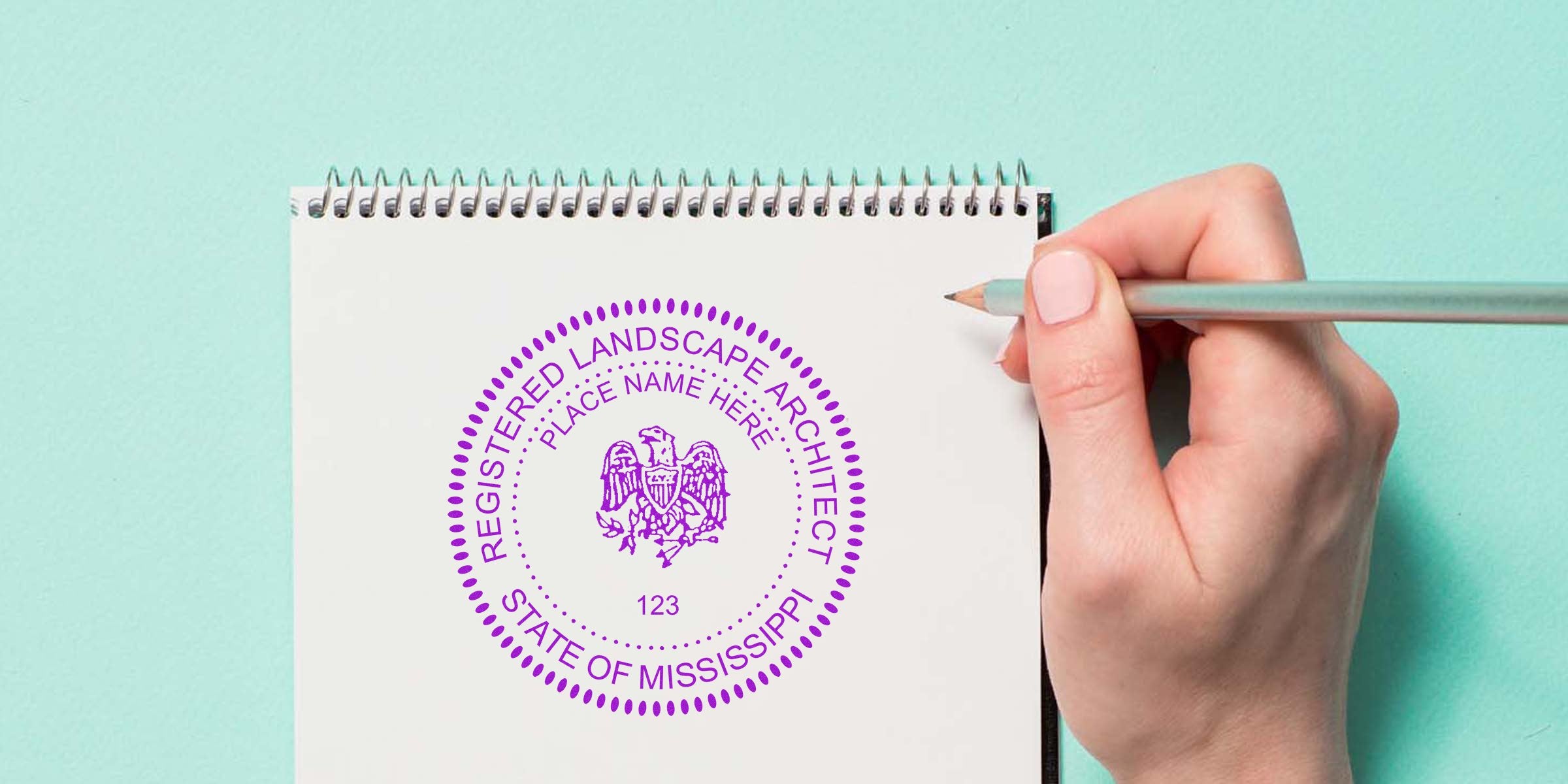 Hand holding pencil over white notebook with Mississippi registered landscape architect seal, securing professional certification logo.