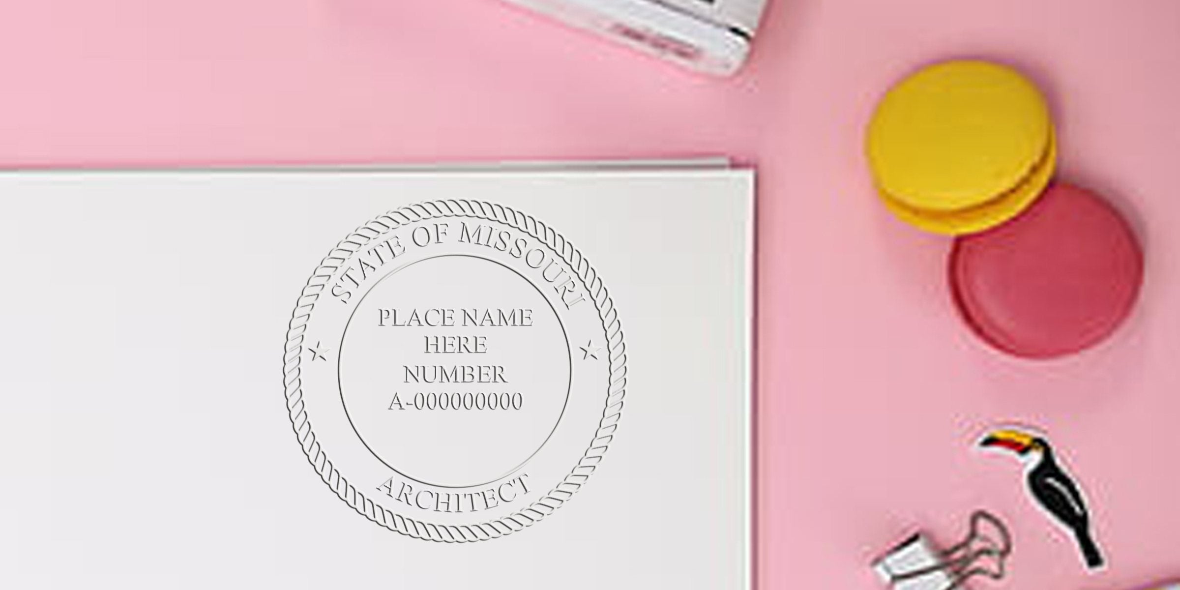Missouri architect seal embossed on white paper with colorful macarons and office supplies on pink background, highlighting architect seal renewal and checklist.
