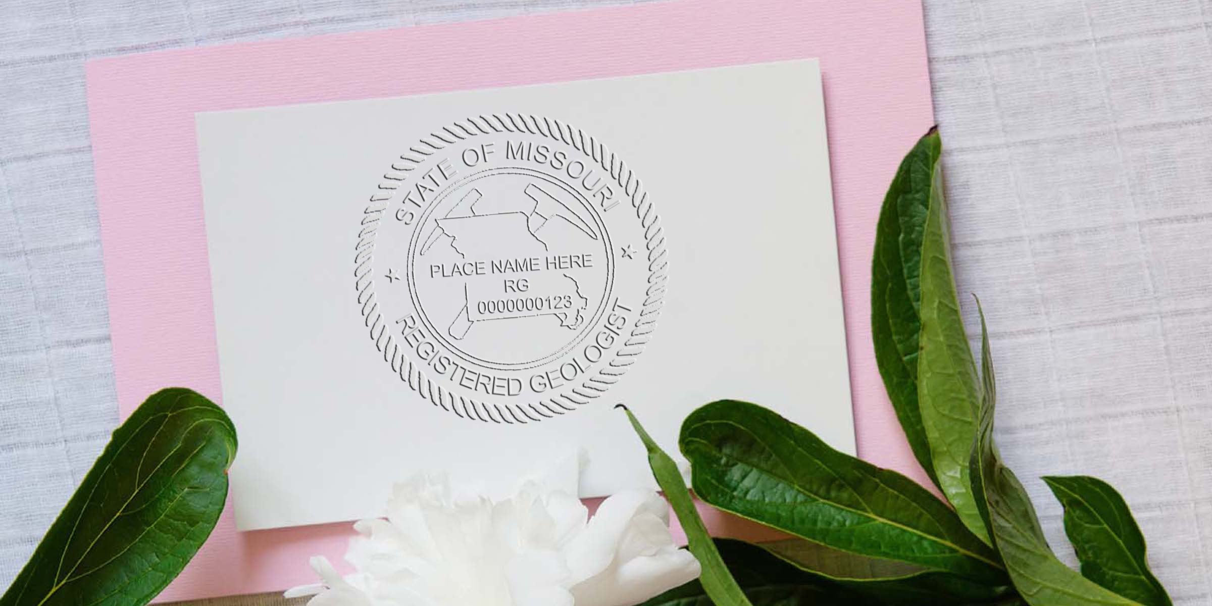 Embossed Missouri Geologist Stamp on white paper with green leaves and pink background, featuring the Missouri Geologist Stamp design per the Stamp Design Guide.