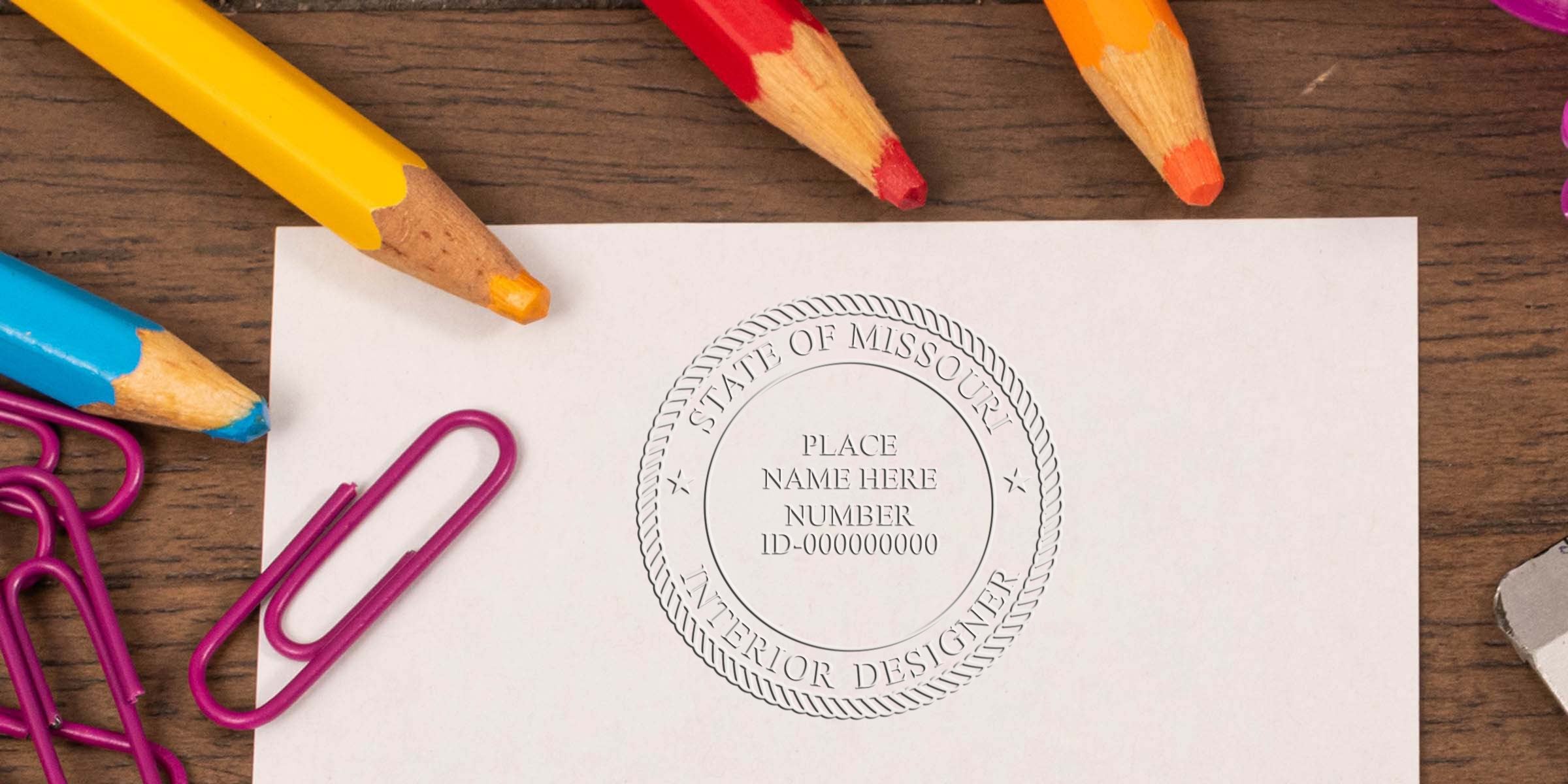 Missouri Interior Designer Seal on paper with colorful pencils and purple paperclips on a wooden desk, symbolizing Interior Design Certification in Missouri.