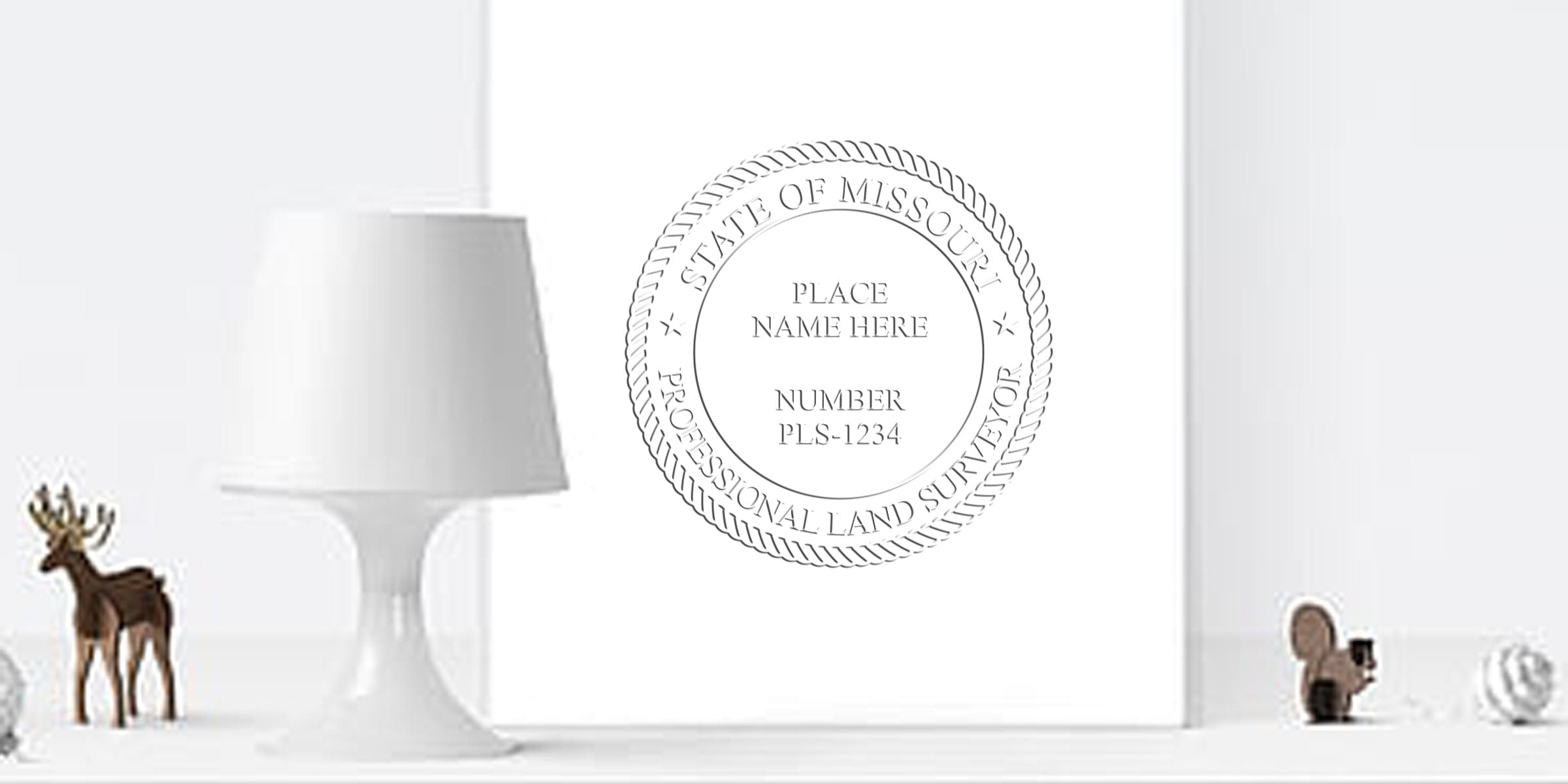 Missouri land surveyor seal on a white wall, next to a modern white lamp and wooden animal figurines.