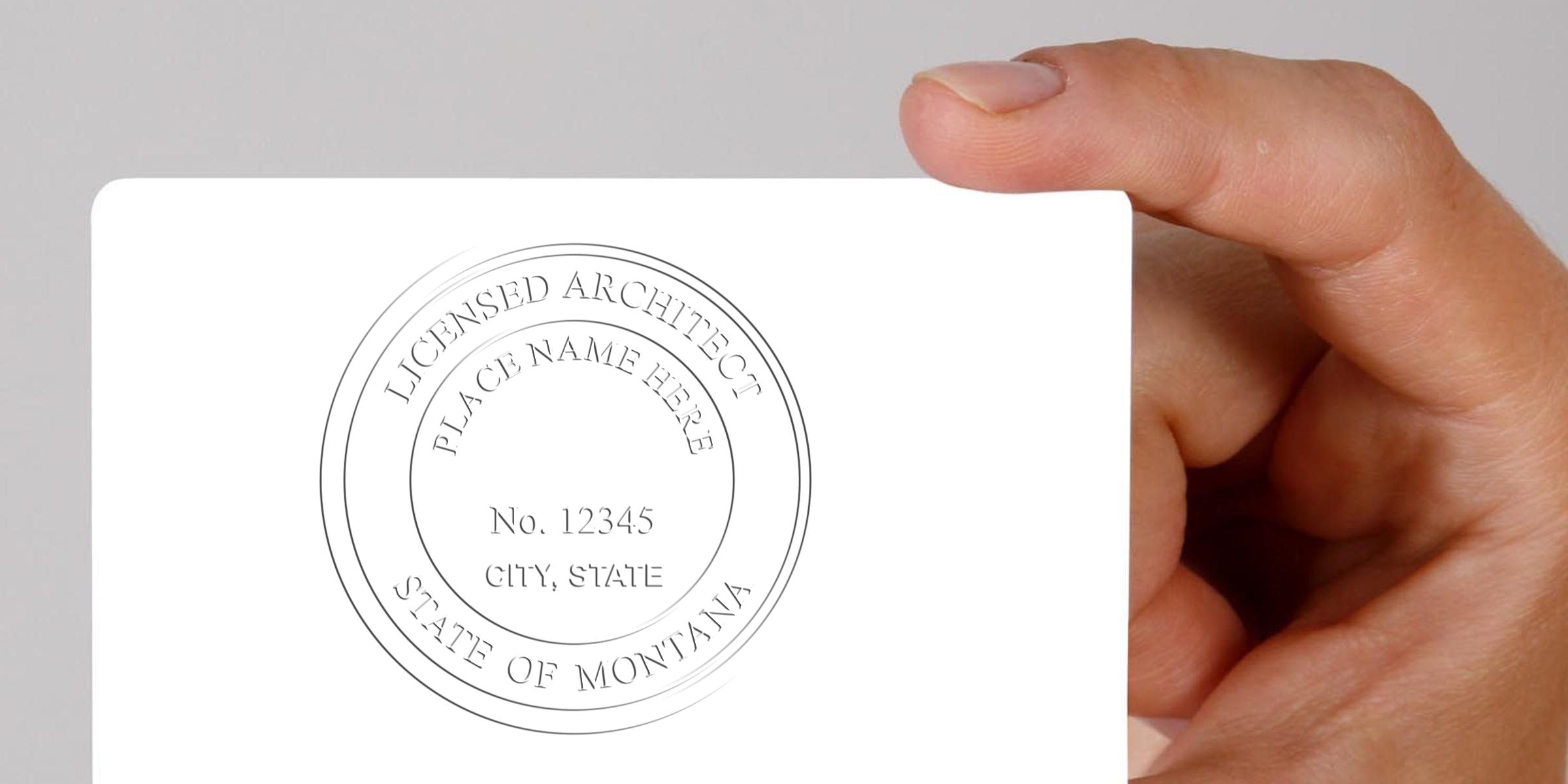 Hand holding Montana architect seal embosser for architect seal stamping and Montana state architect license verification.