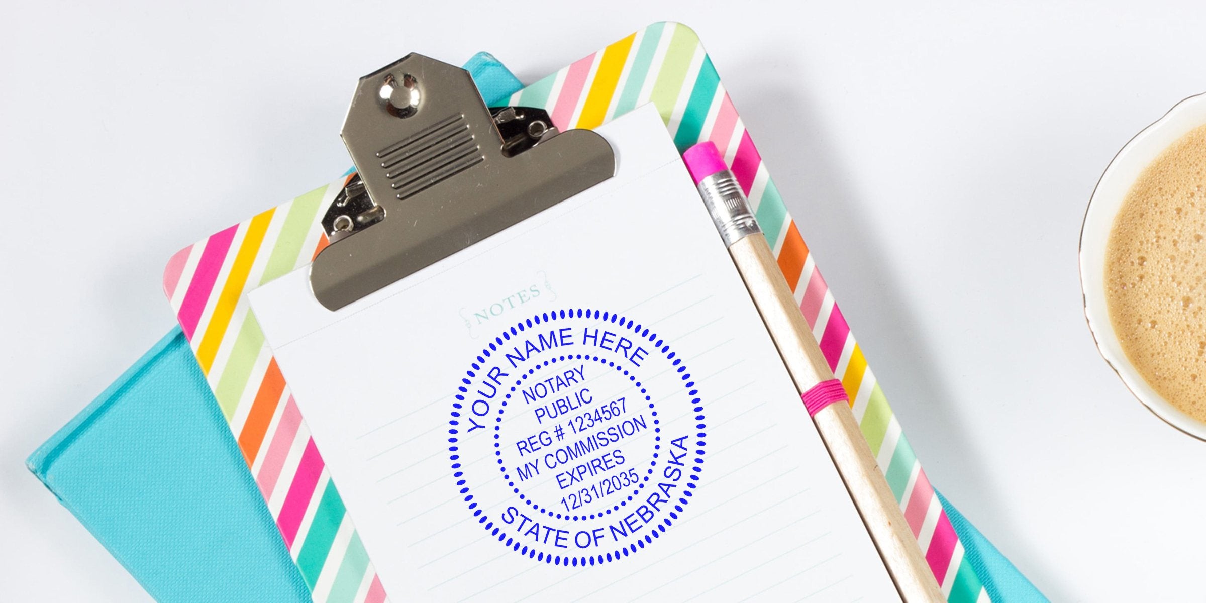 Nebraska notary stamp on clipboard with colorful stripes, pencil, coffee cup, and Nebraska notary commission seal, showing a self-inking notary stamp.