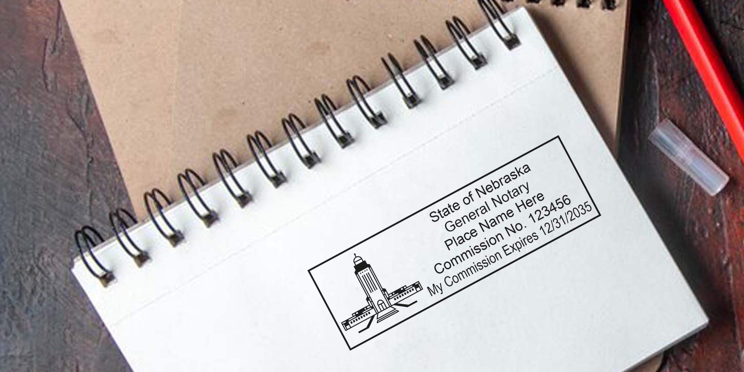Nebraska notary seal stamped on white spiral notebook with red pen, official commission seal, and notary certification document, symbolizing trusted notary services.
