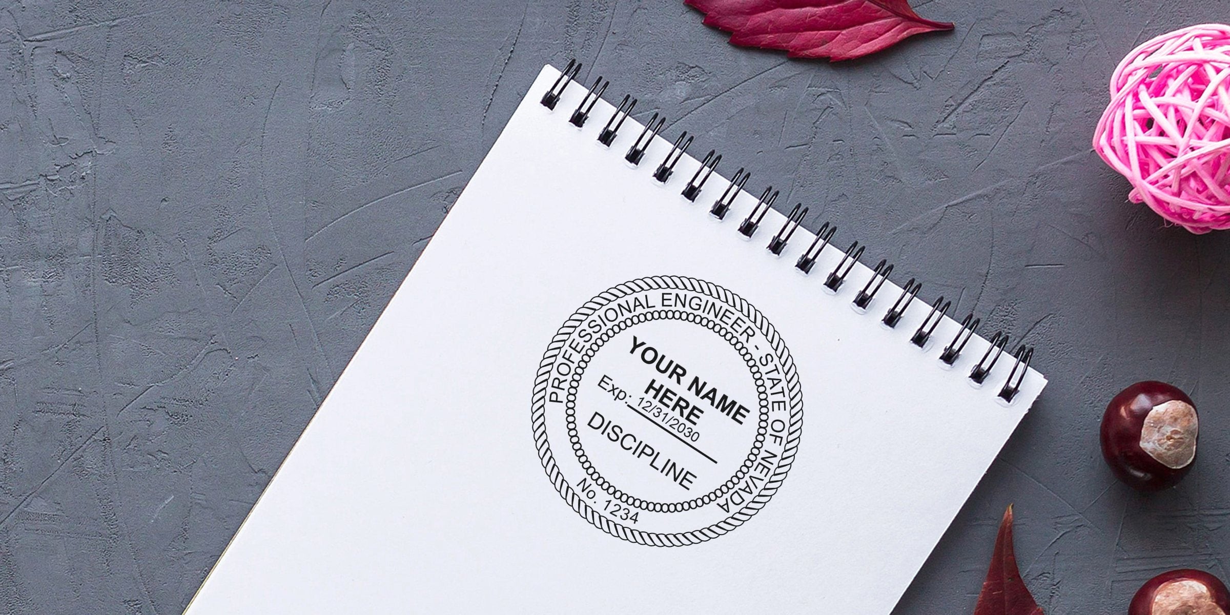 Nevada engineer stamp on spiral notebook with autumn leaves and chestnuts on gray textured background, emphasizing engineer seal requirements.