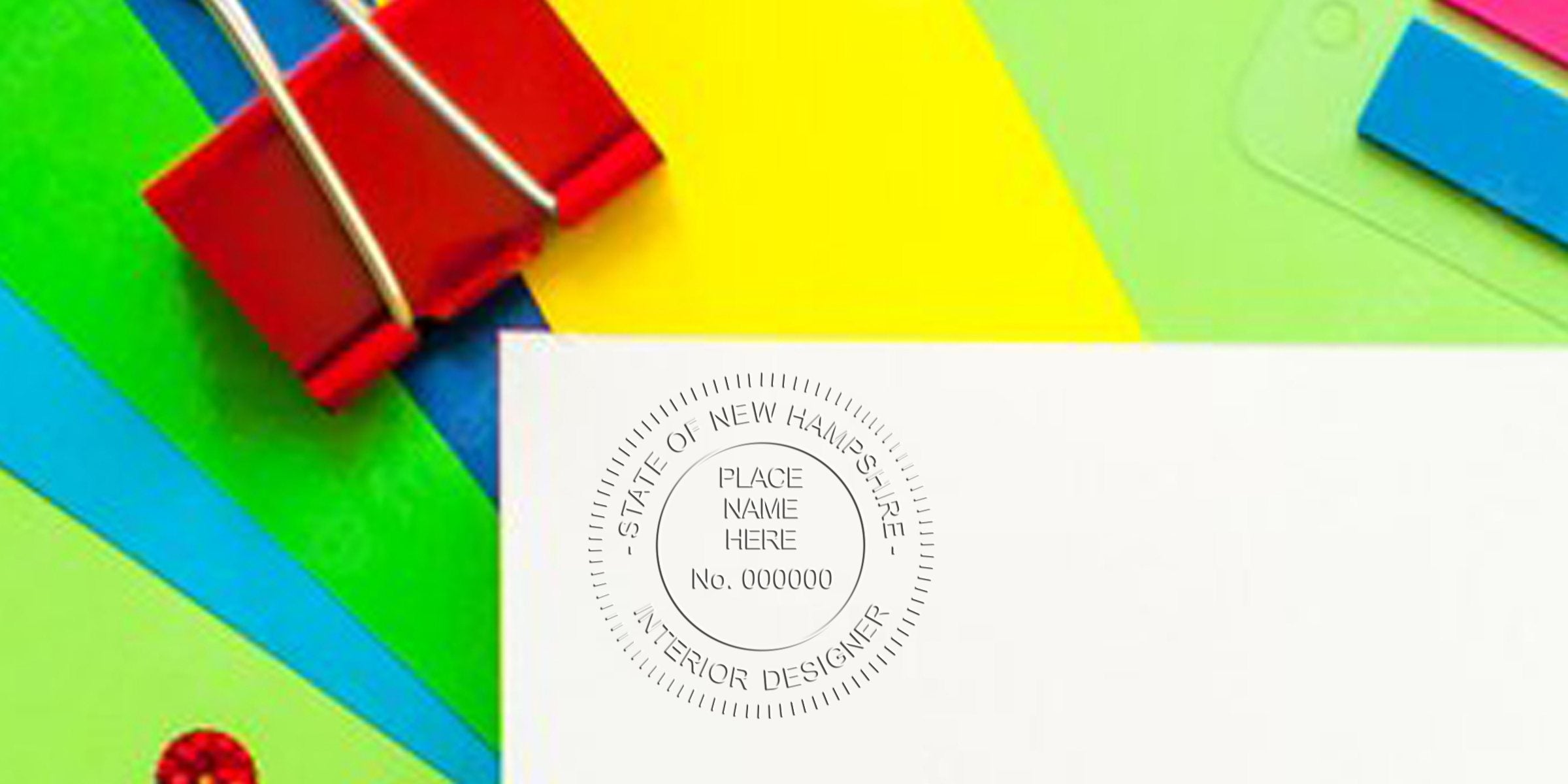 Red binder clip on colorful paper with an interior designer seal, surrounded by office supplies for a creative workspace by a New Hampshire interior designer.