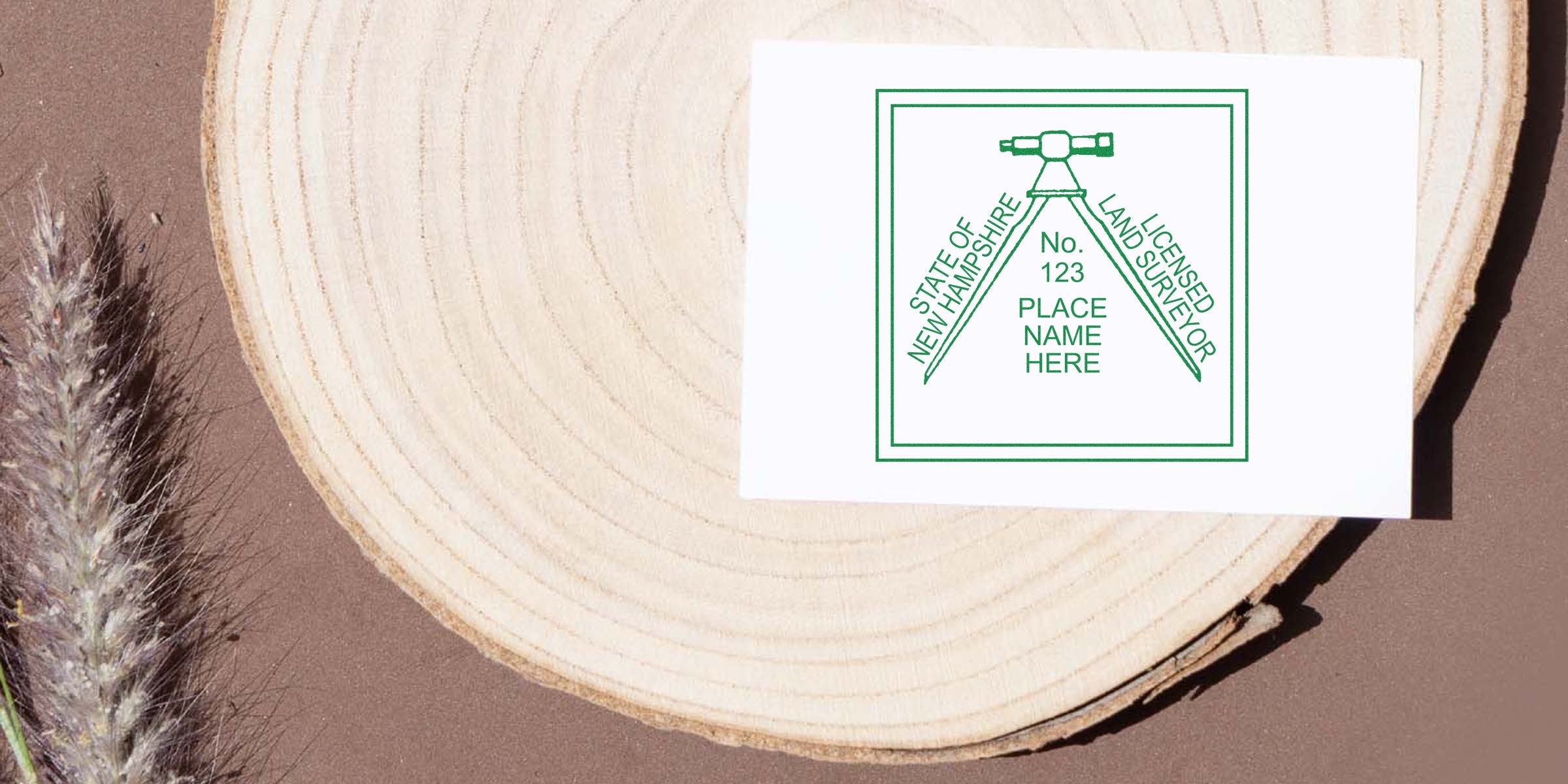 New Hampshire land surveyor business card on wood with dried grass, showcasing professional surveying services and highlighting NH land surveyor stamp and its requirements.