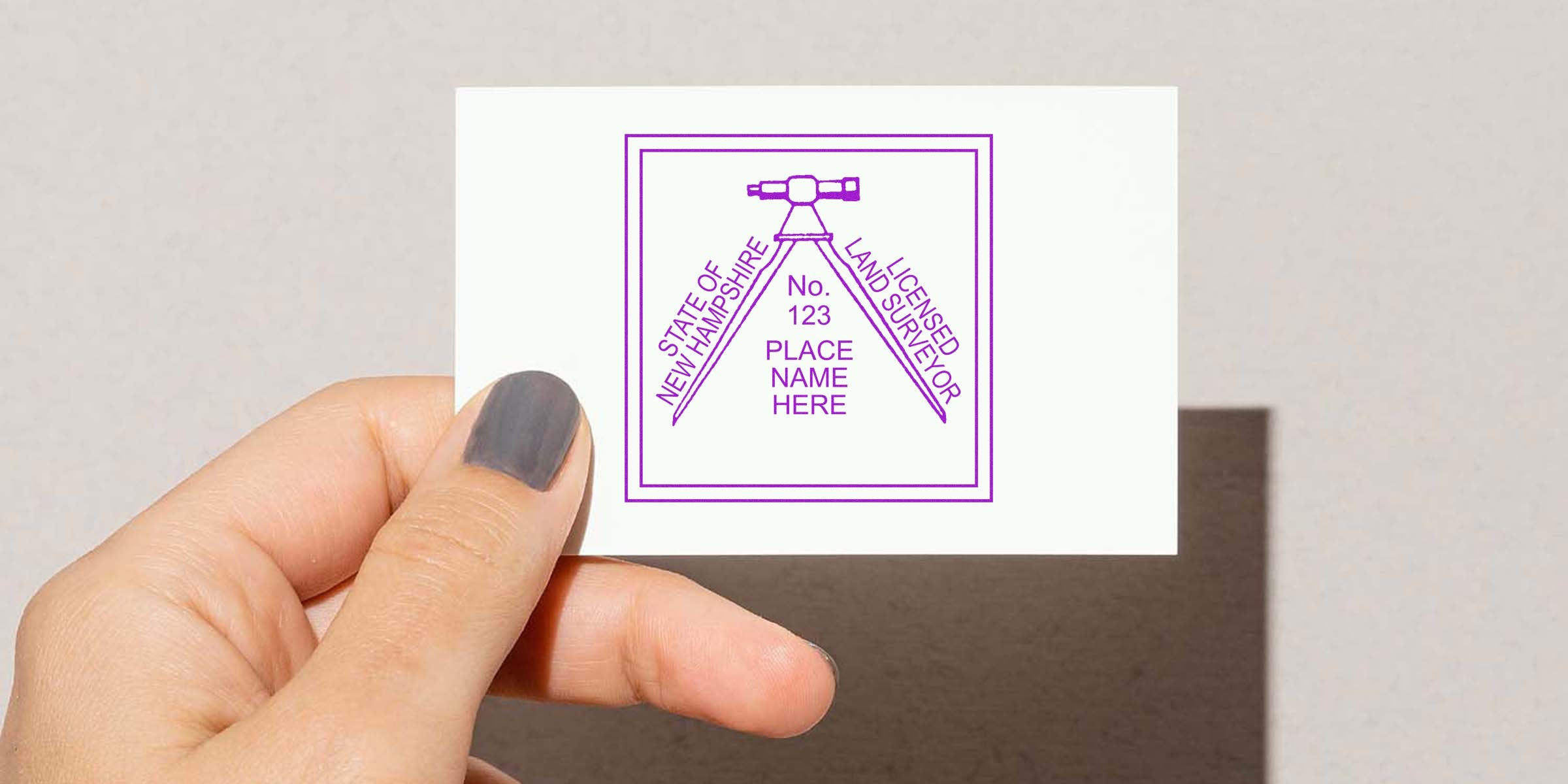 Hand holding a business card with a New Hampshire land surveyor stamp, symbolizing a professional guide for state land survey services.