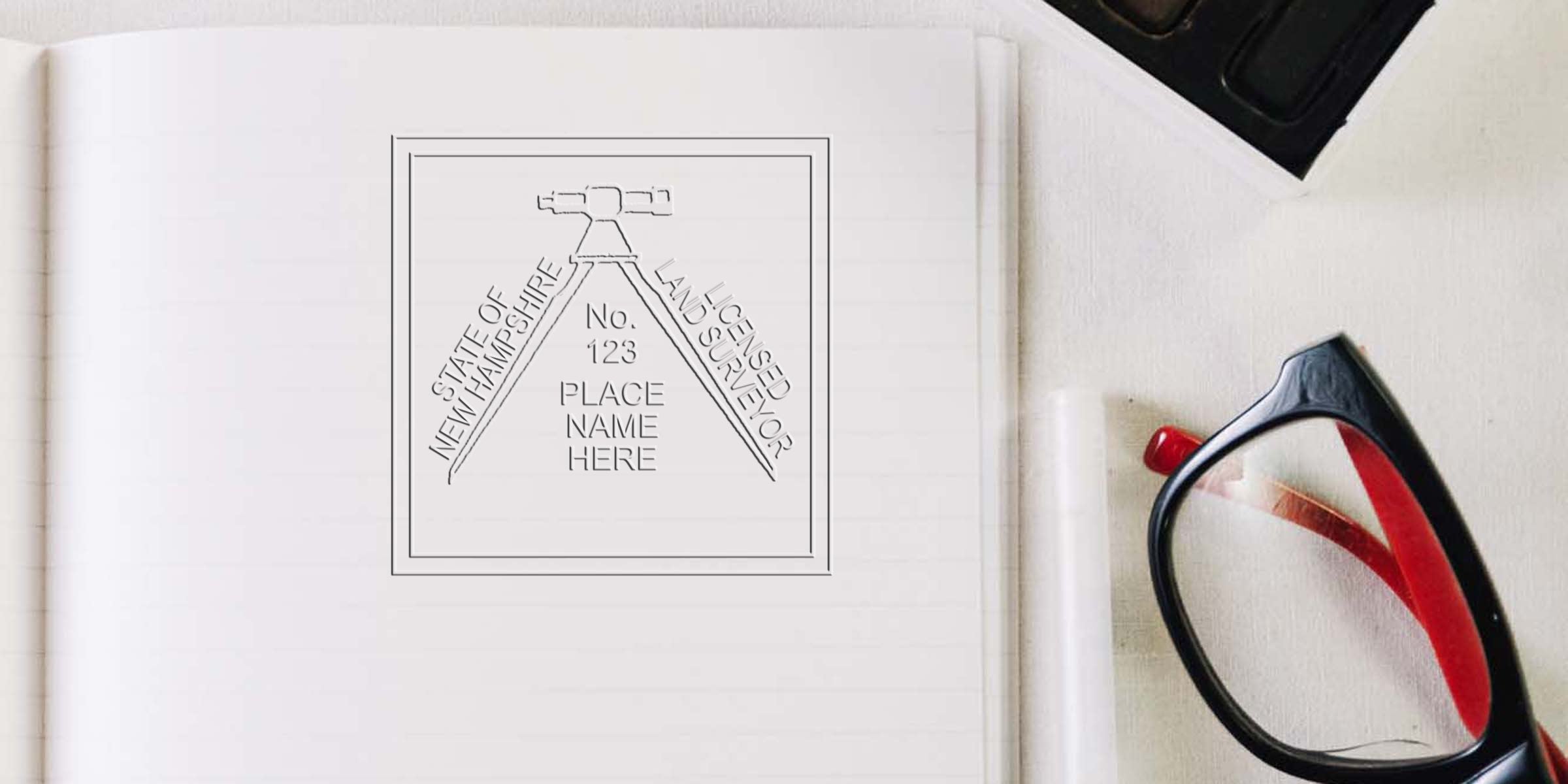 Licensed land surveyor emblem on notebook with glasses and watercolor palette, showing New Hampshire land surveyor stamp size and NH land surveyor stamp requirements for surveying services.