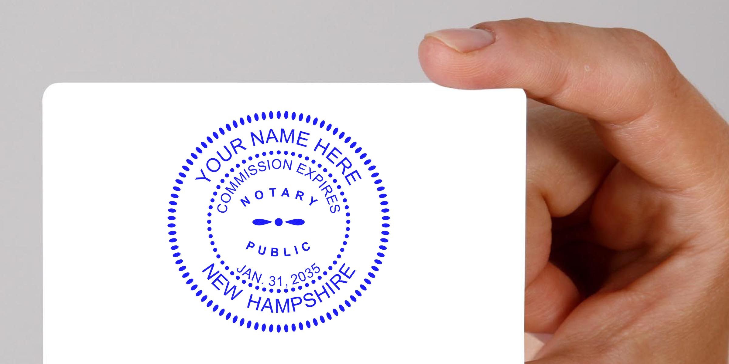 Hand holding New Hampshire notary seal stamp displaying commission expiration date, in compliance with notary public guidelines.
