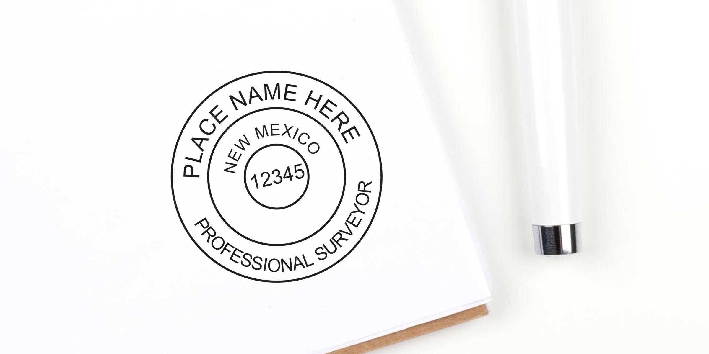 New Mexico land surveyor stamp with place name and license number on white paper beside a white pen, meeting all land surveyor stamp requirements.