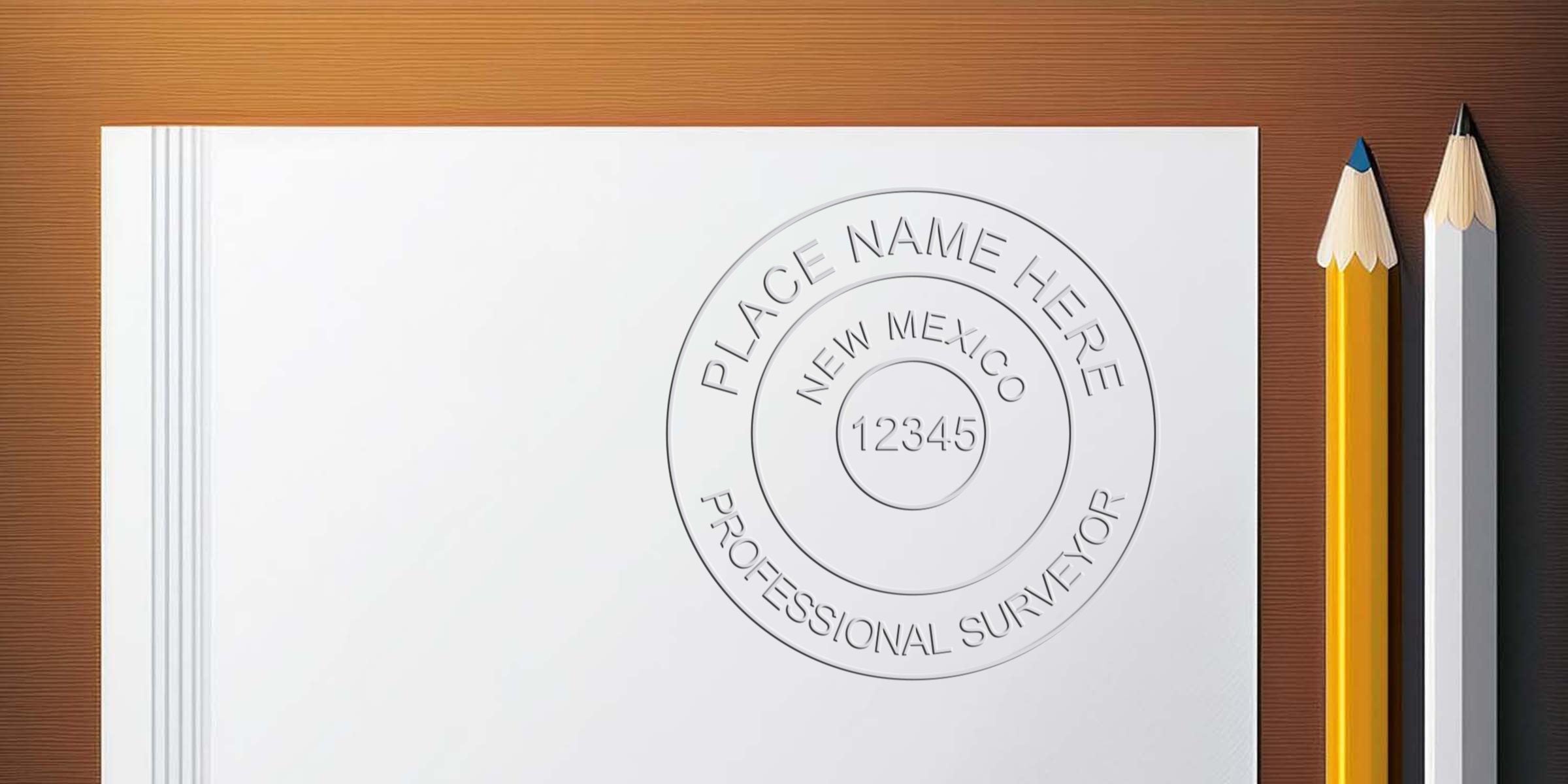 New Mexico land surveyor seal embossed on white paper with yellow and white pencils on a wooden background, emphasizing land surveyor seal requirements.